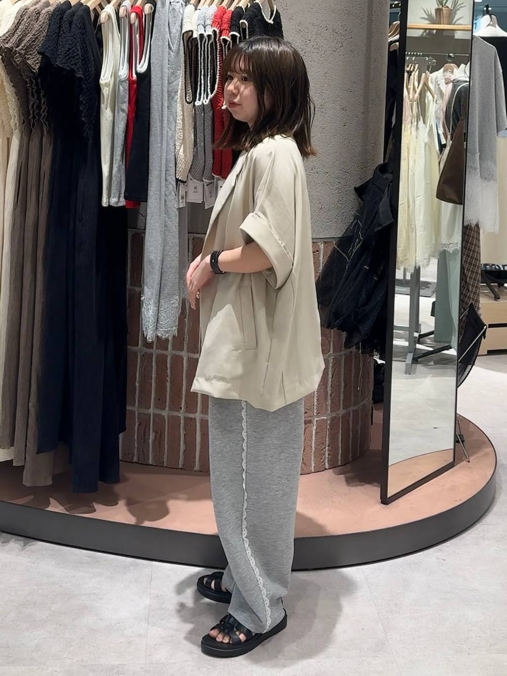 グレー系のスウェットパンツ、ホワイト系のテーラードジャケット、ブラック系のサンダルを着用したレディースの夏コーディネートの2枚目の写真