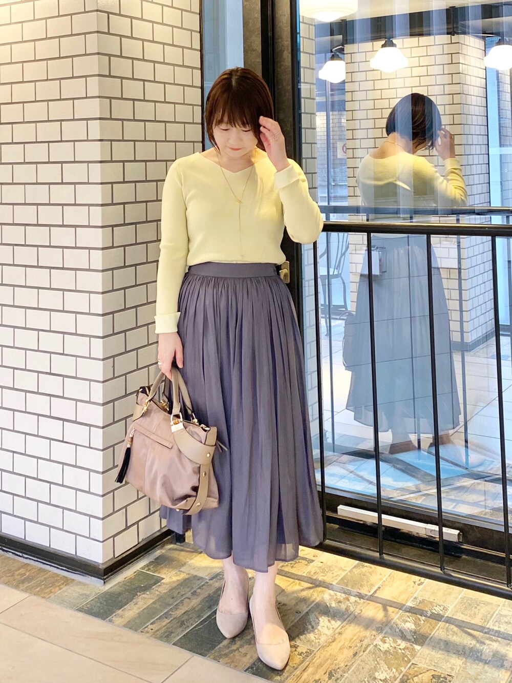 イエロー系のニット/セーター、グレー系のその他アウター、グレー系のスカートを着用したレディースの冬コーディネートの2枚目の写真