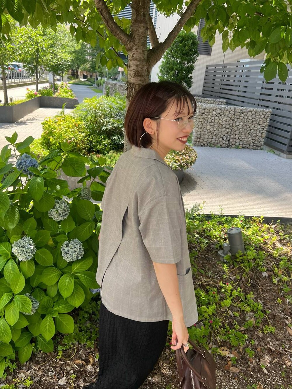 ブラック系のタンクトップ、ブラウン系のショルダーバッグ、ベージュ系のテーラードジャケットを着用したレディースの夏コーディネートの2枚目の写真