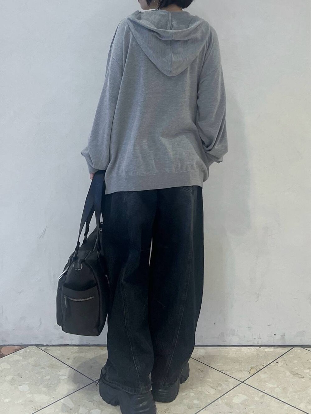 グレー系のパーカー、ブルー系のデニムパンツ、ブラック系のスニーカーを着用したレディースの秋コーディネートの3枚目の写真
