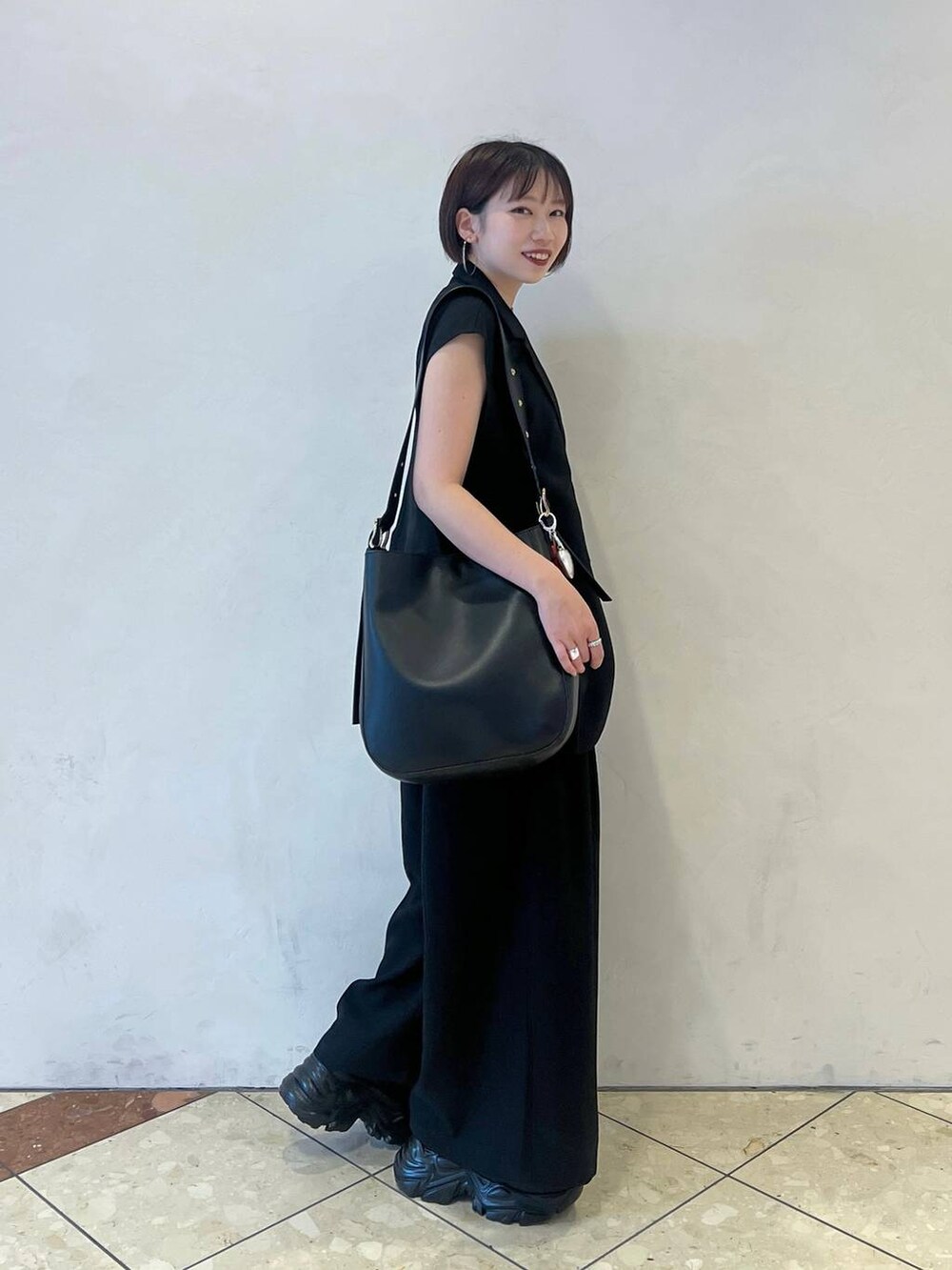 ブラック系のスニーカー、ブラック系のショルダーバッグ、グリーン系のタンクトップを着用したレディースの春コーディネートの2枚目の写真