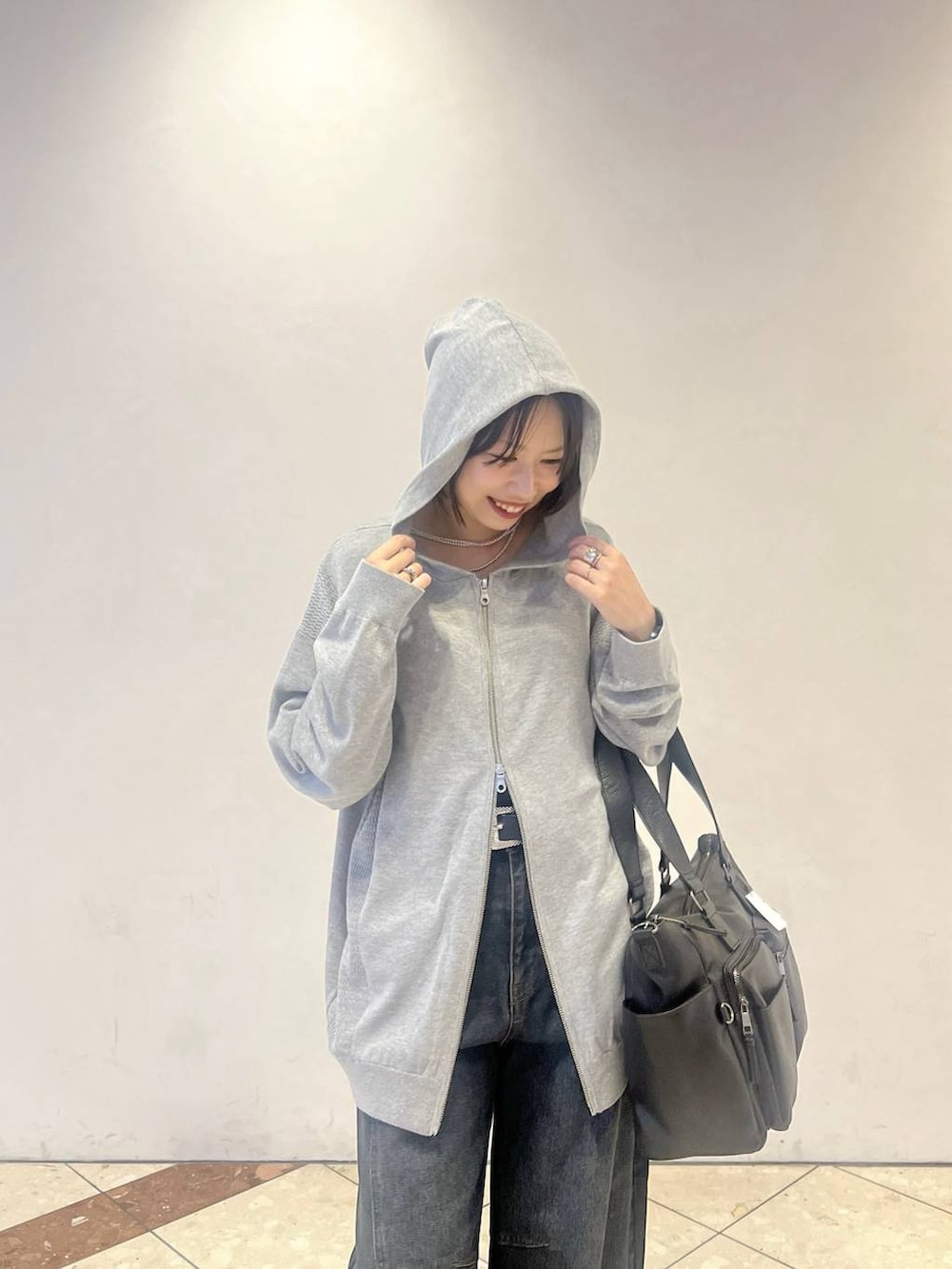 グレー系のパーカー、ブルー系のデニムパンツ、ブラック系のスニーカーを着用したレディースの秋コーディネートの2枚目の写真
