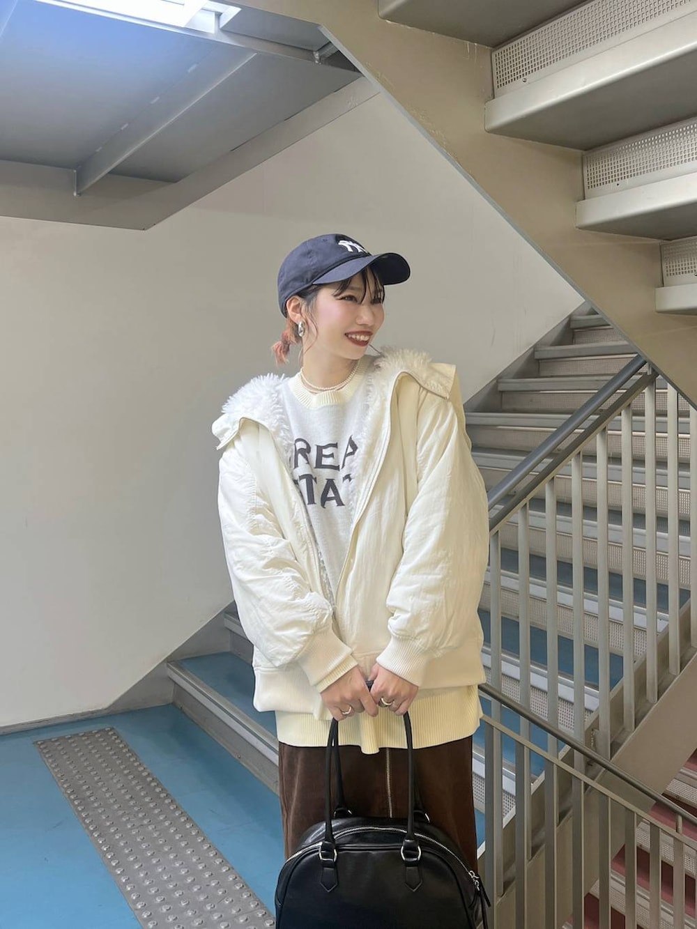 ブラック系のスニーカー、ホワイト系のブルゾン、ブラック系のボストンバッグを着用したレディースの秋コーディネートの3枚目の写真