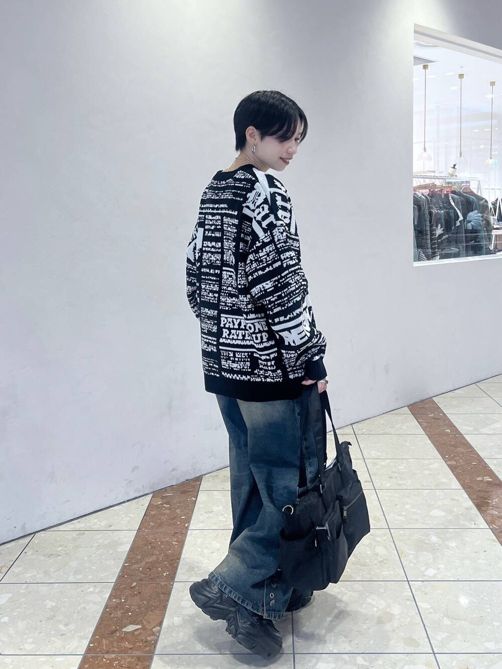ブラック系のスニーカー、ブルー系のデニムパンツ、ブラック系のボストンバッグを着用したレディースの秋コーディネートの3枚目の写真