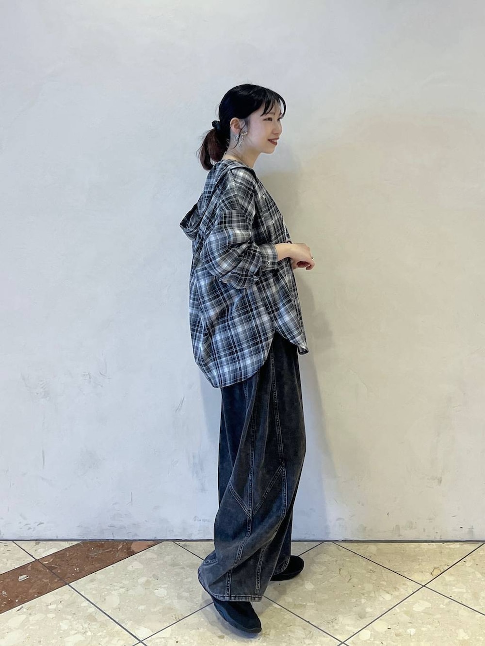 ブラック系のスニーカー、ブラック系のデニムパンツ、ブラウン系のショルダーバッグを着用したレディースの春コーディネートの2枚目の写真