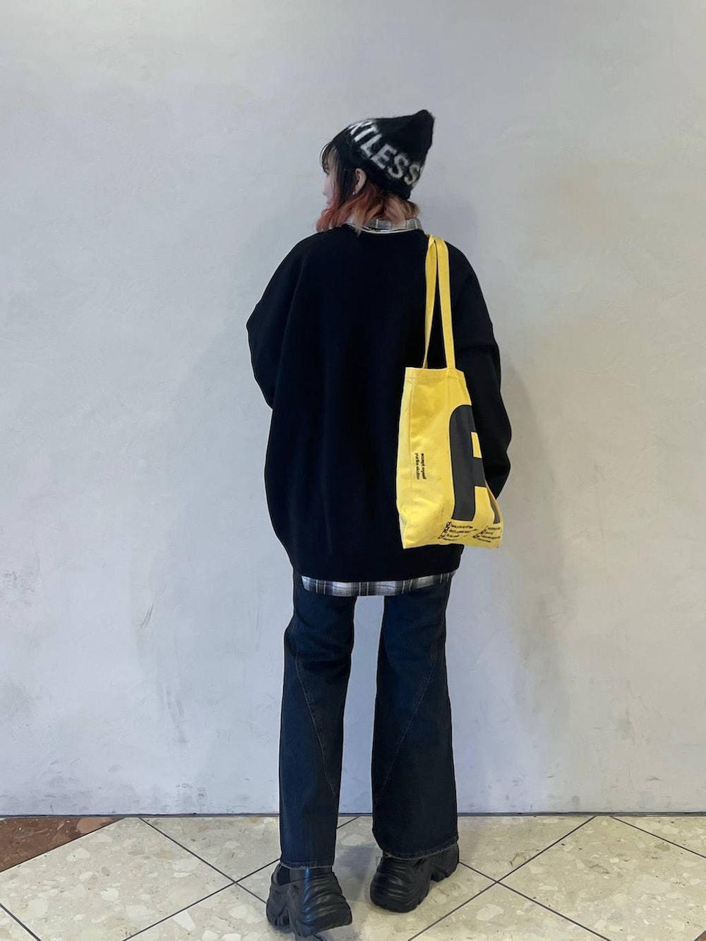 ブラック系のブーツ、ブラック系のニット/セーター、ブルー系のデニムパンツを着用したレディースの秋コーディネートの3枚目の写真