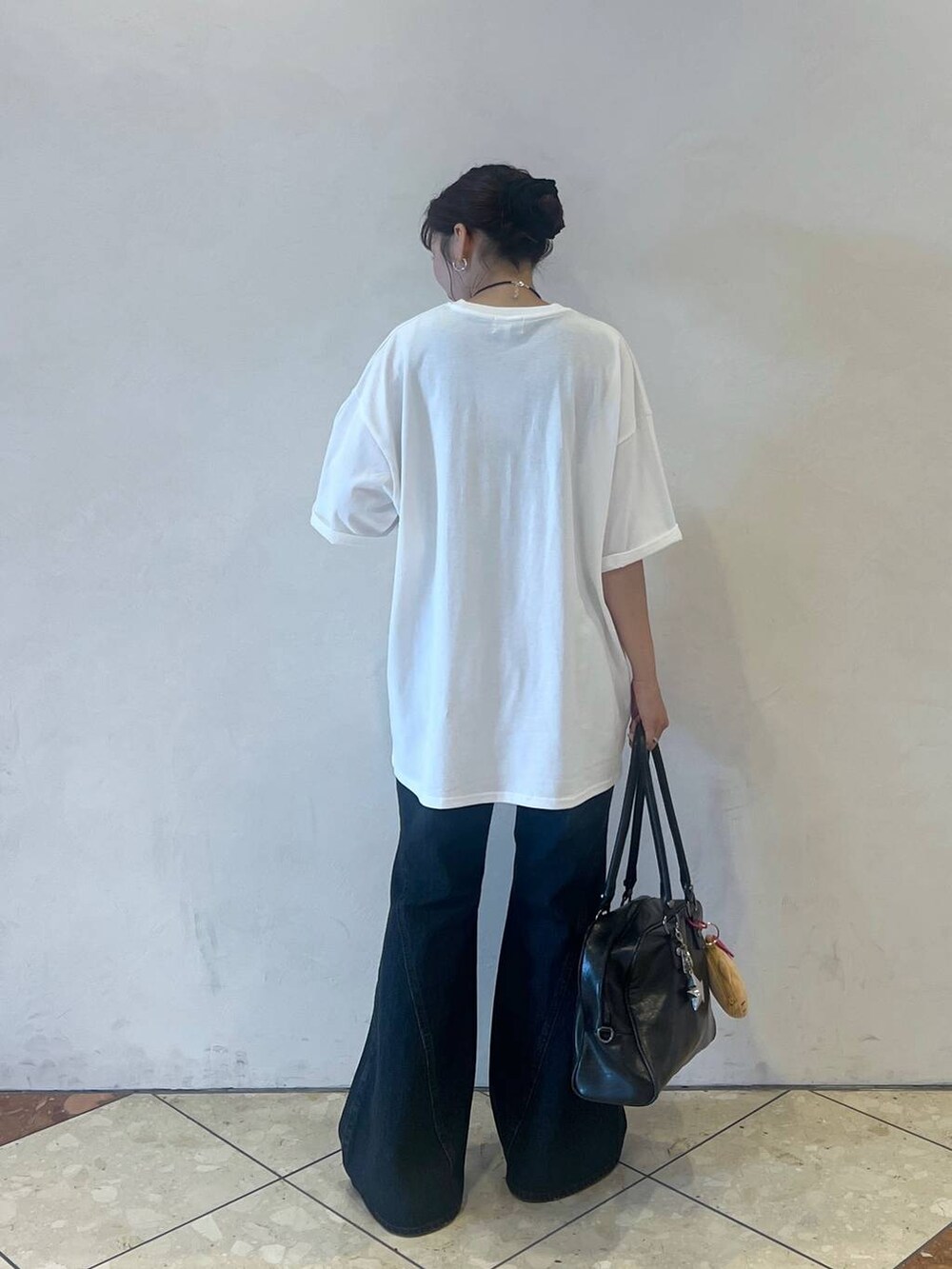 ブラック系のボストンバッグ、ホワイト系のTシャツ/カットソー、ブルー系のデニムパンツを着用したレディースの夏コーディネートの2枚目の写真