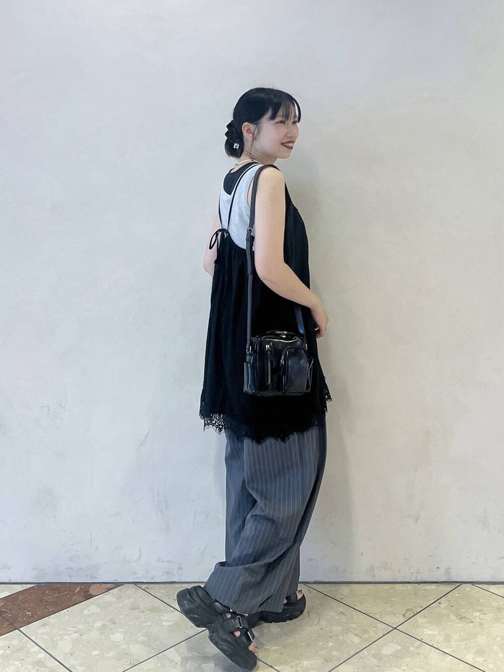 ブラック系のショルダーバッグ、ブラック系のサンダル、グレー系のタンクトップを着用したレディースの夏コーディネートの2枚目の写真
