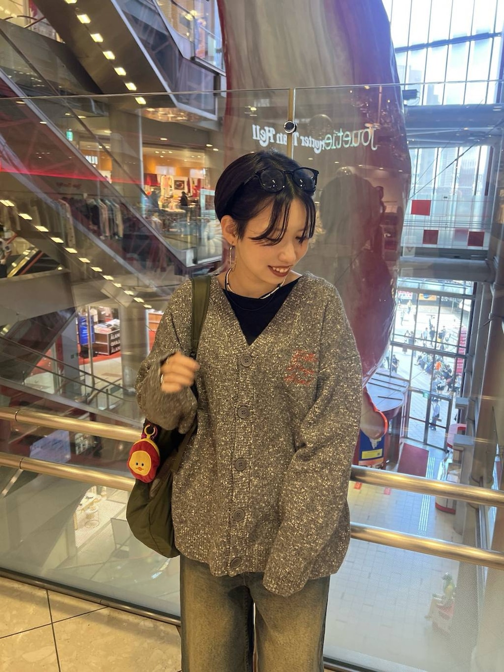 ブルー系のデニムパンツ、グレー系のカーディガン/ボレロ、ブラック系のTシャツ/カットソーを着用したレディースの秋コーディネートの2枚目の写真