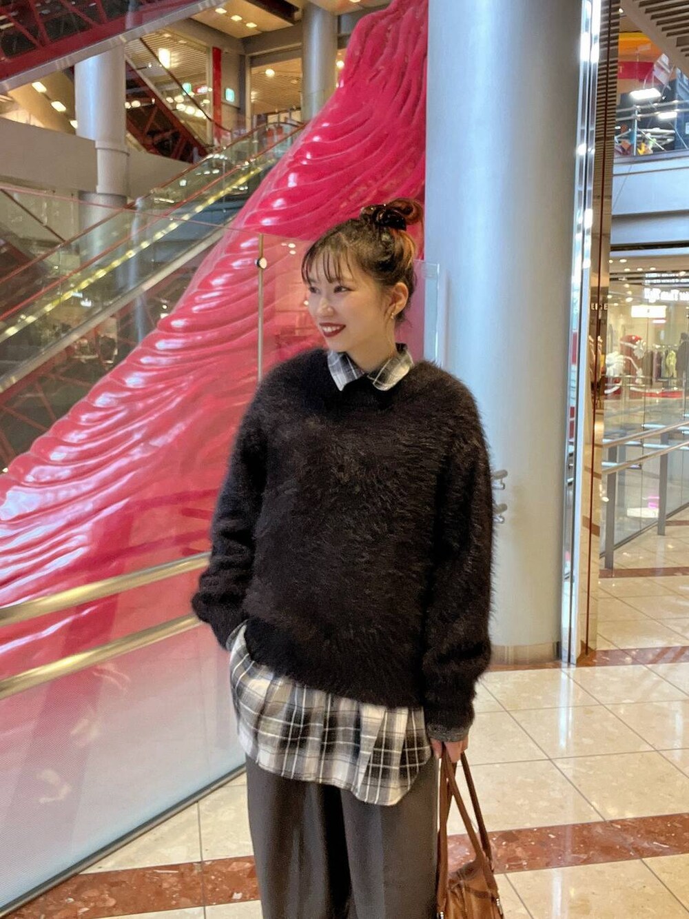 グレー系のスニーカー、イエロー系のボストンバッグ、ブラック系のニット/セーターを着用したレディースの秋コーディネートの2枚目の写真