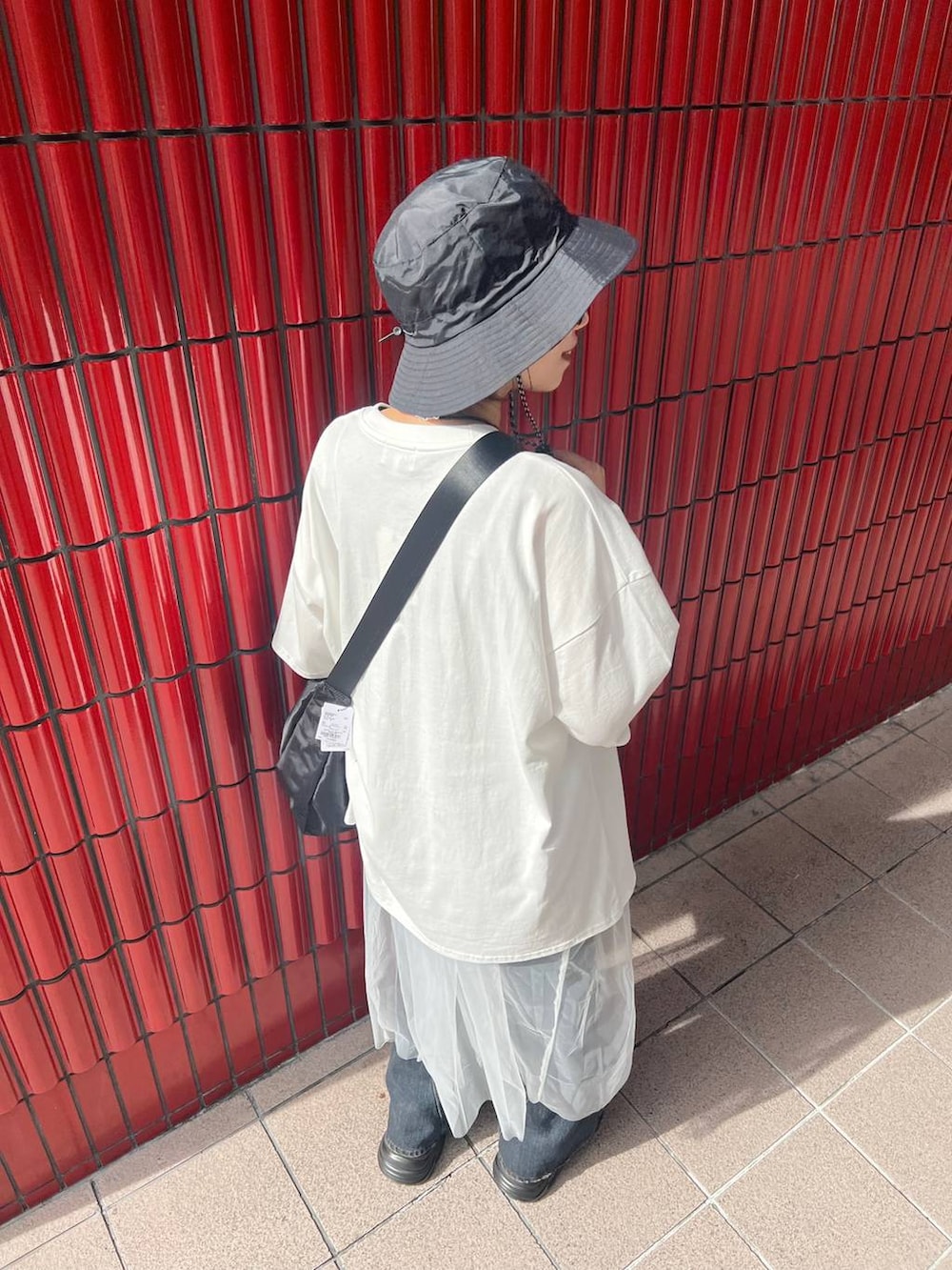 ブラック系のスニーカー、ブラック系のショルダーバッグ、ブルー系のデニムパンツを着用したレディースの夏コーディネートの5枚目の写真