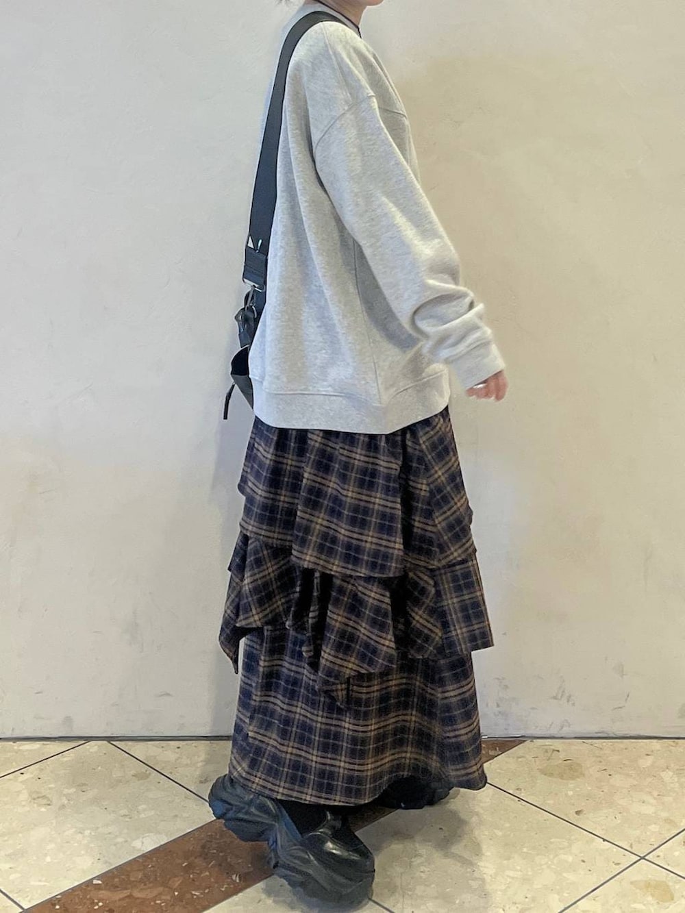 ブラック系のブーツ、グリーン系のボストンバッグ、ブラウン系のスカートを着用したレディースの冬コーディネートの2枚目の写真