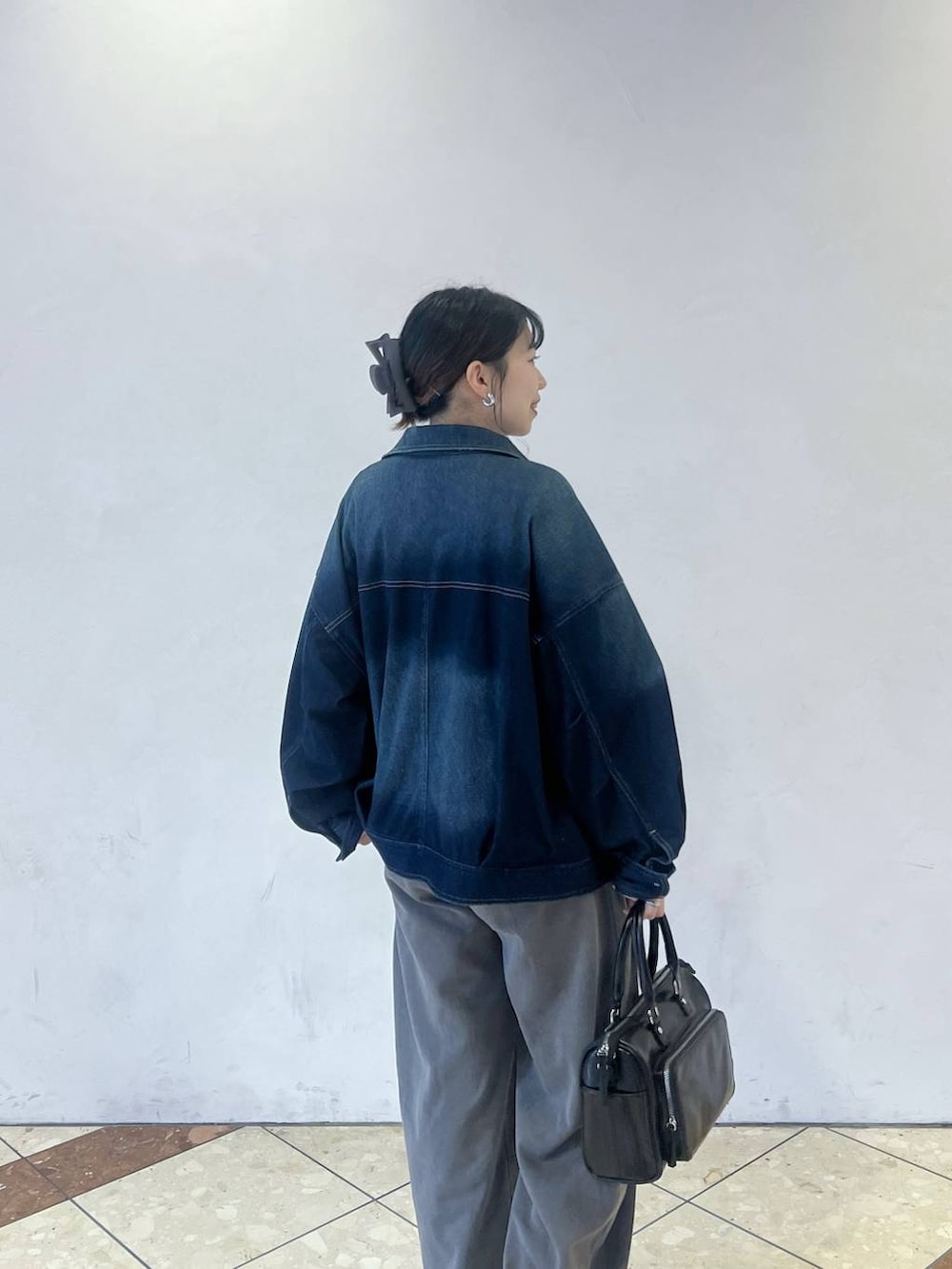 ブルー系のブルゾン、ブラック系のショルダーバッグ、グレー系のスウェットパンツを着用したレディースの春コーディネートの3枚目の写真