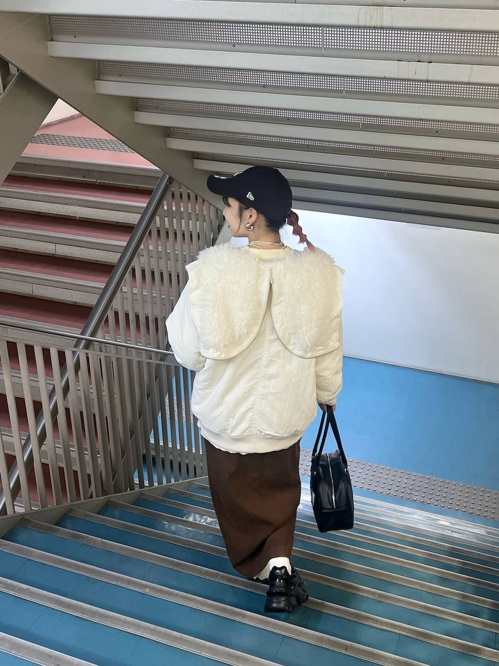 ブラック系のスニーカー、ホワイト系のブルゾン、ブラック系のボストンバッグを着用したレディースの秋コーディネートの2枚目の写真