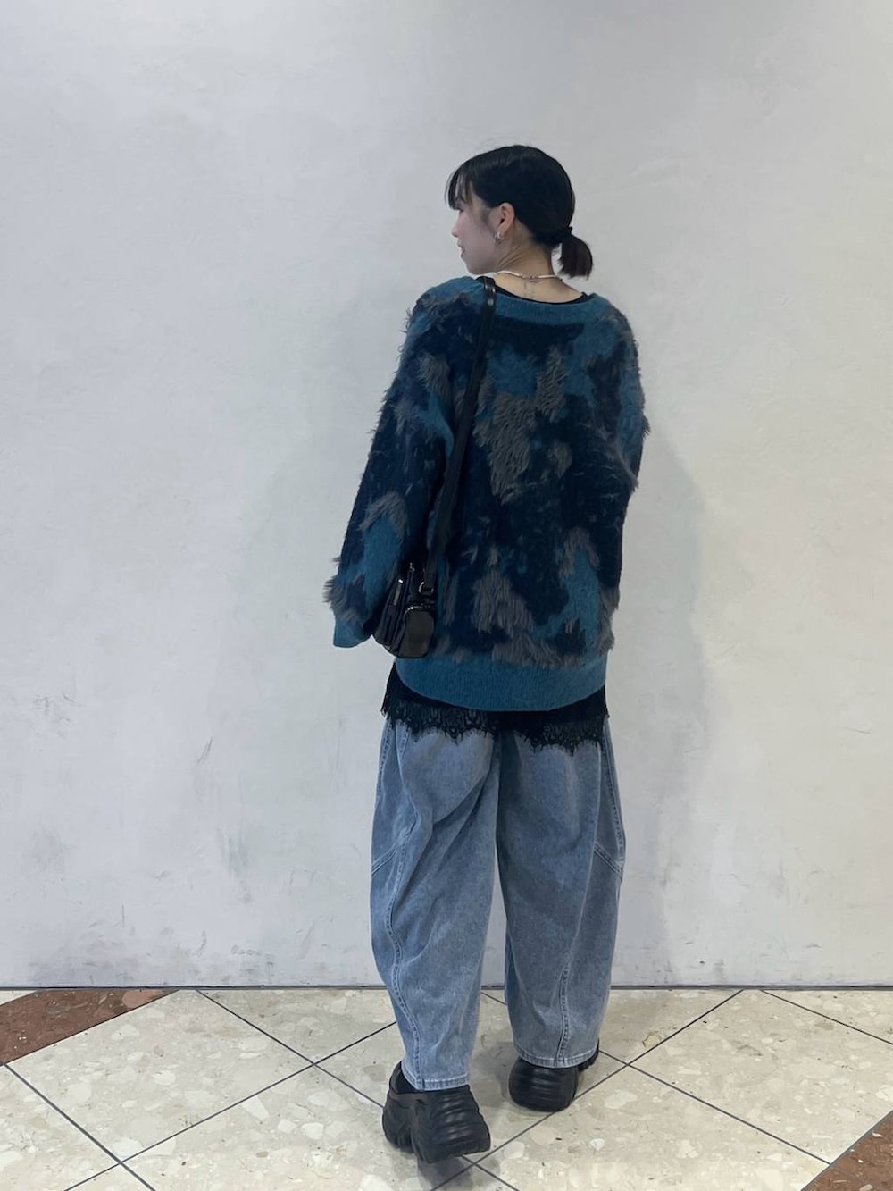 ブラック系のブーツ、ブルー系のデニムパンツ、ブラック系のショルダーバッグを着用したレディースの夏コーディネートの4枚目の写真