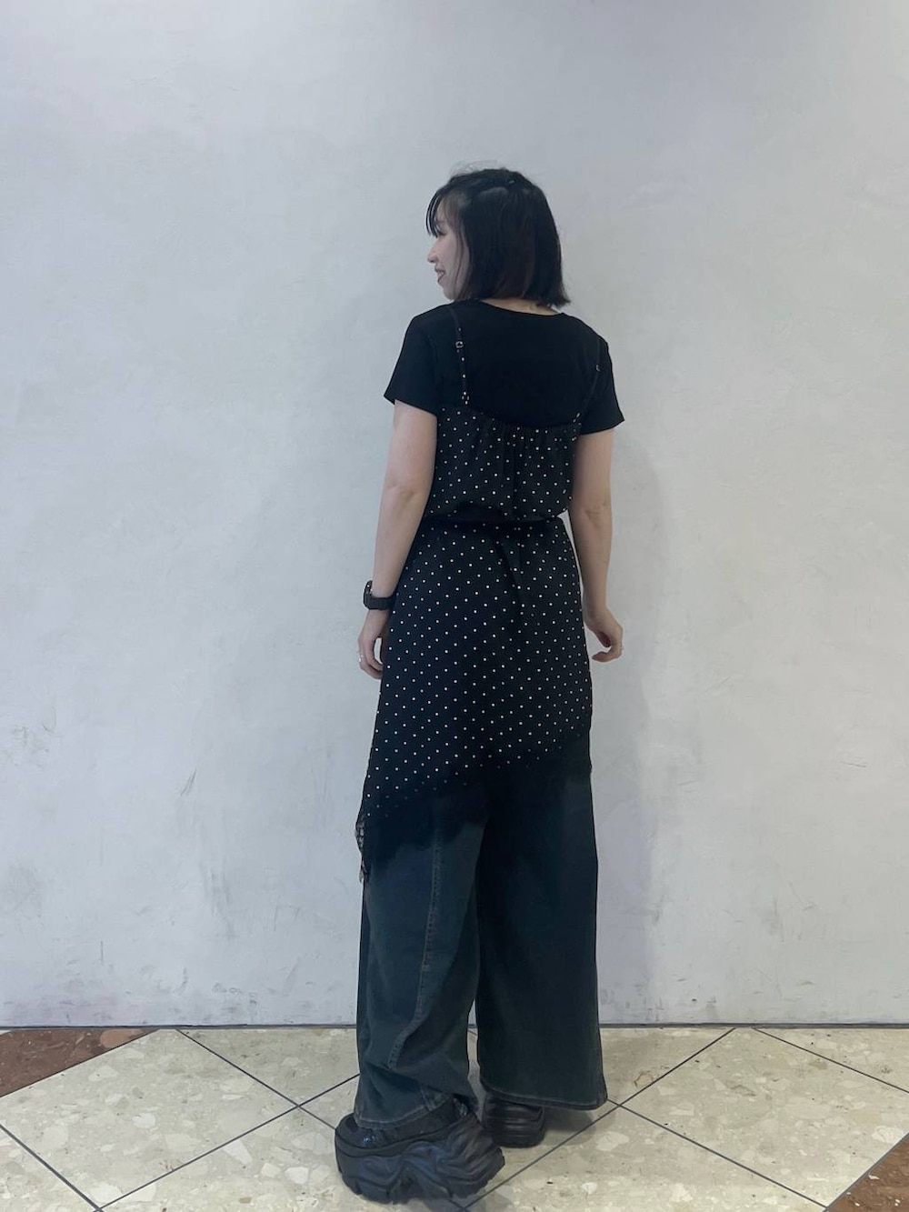 グリーン系のデニムパンツ、ブラック系のチュニック、ブラック系のスニーカーを着用したレディースの夏コーディネートの3枚目の写真