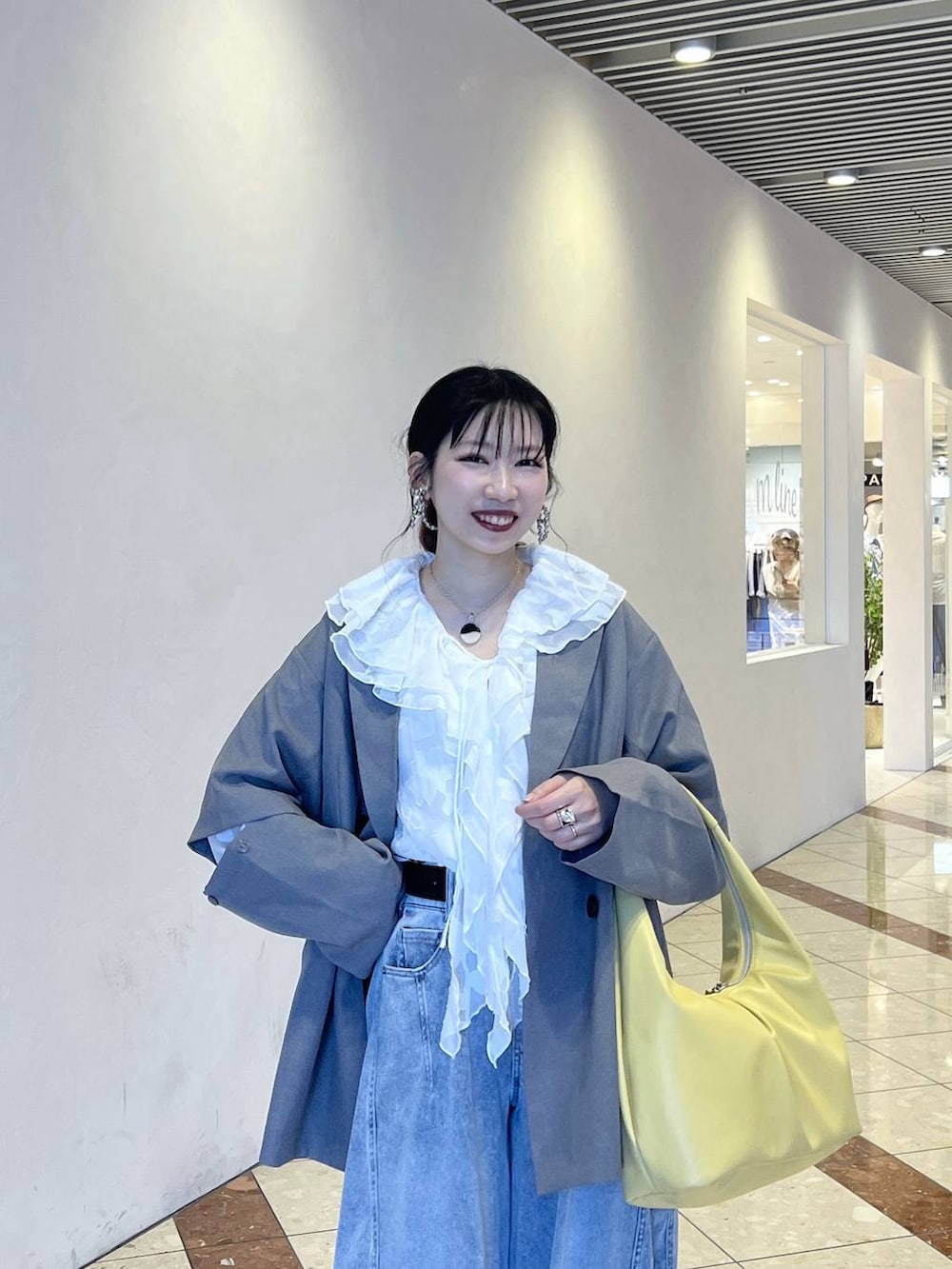 ブラック系のスニーカー、イエロー系のトートバッグ、グレー系のテーラードジャケットを着用したレディースの春コーディネートの3枚目の写真