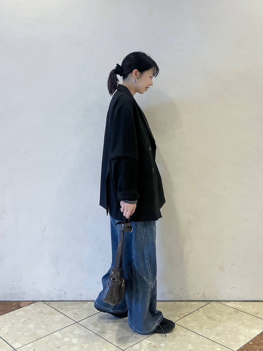 ブラック系のスニーカー、ブラック系のテーラードジャケット、グレー系のショルダーバッグを着用したレディースの春コーディネートの2枚目の写真