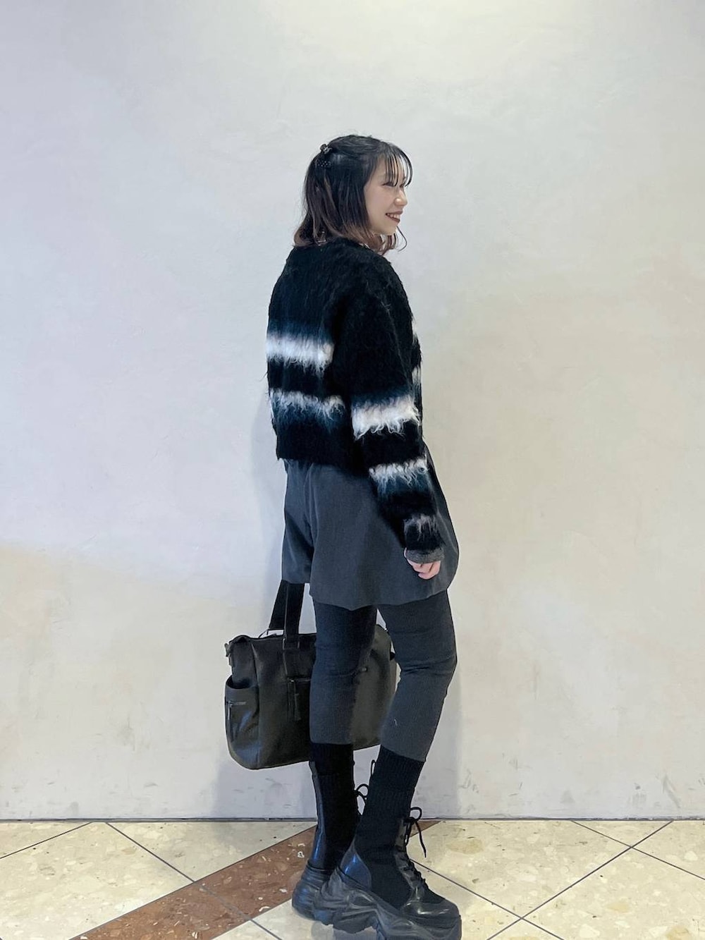 ブラック系のブーツ、グリーン系のボストンバッグ、グレー系のその他パンツを着用したレディースの冬コーディネートの2枚目の写真