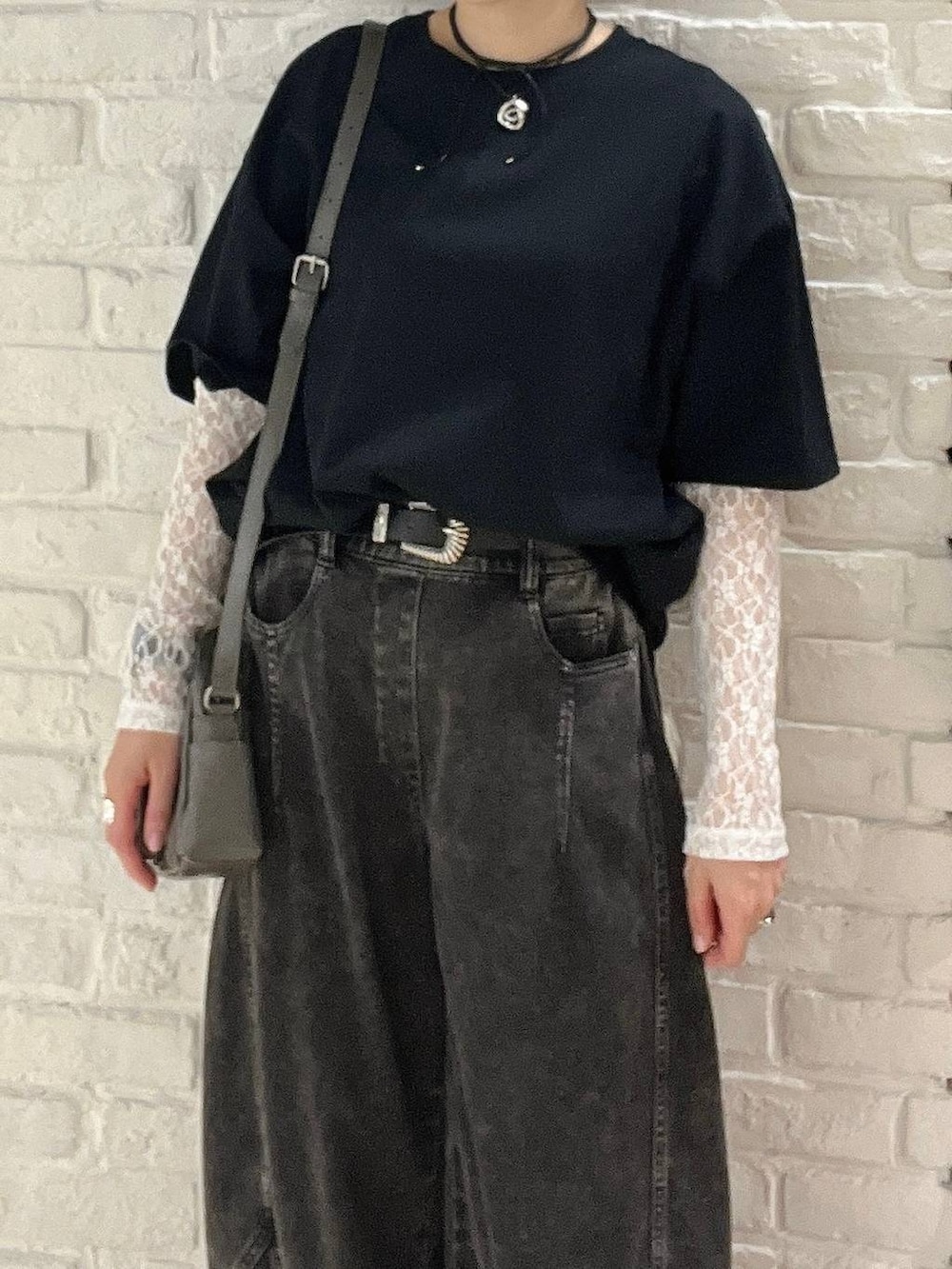 ブラック系のデニムパンツ、グレー系のショルダーバッグ、ブラック系のTシャツ/カットソーを着用したレディースの春コーディネートの2枚目の写真