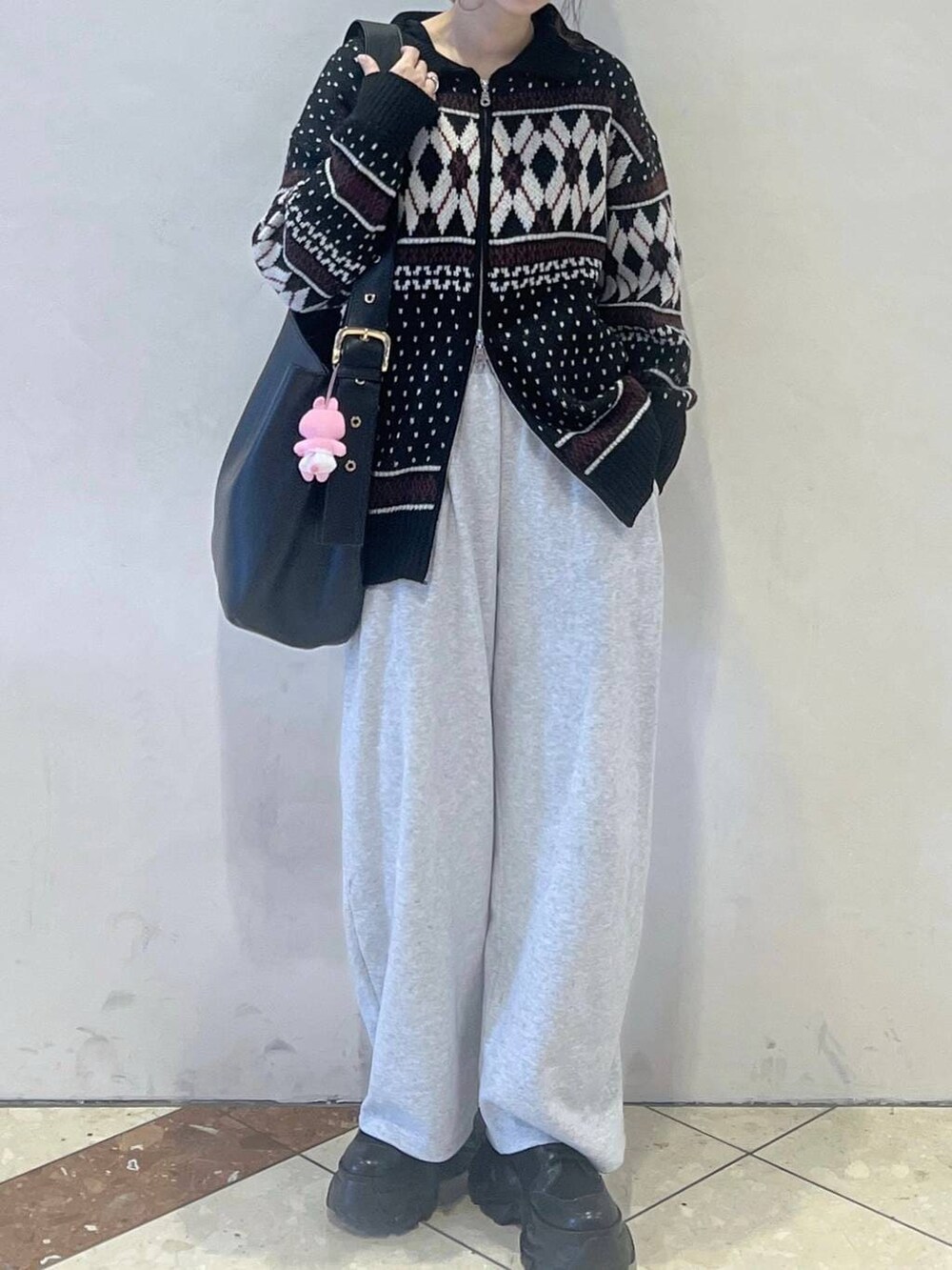 ブラック系のブーツ、ブラック系のショルダーバッグ、グレー系のスウェットパンツを着用したレディースの冬コーディネートの2枚目の写真