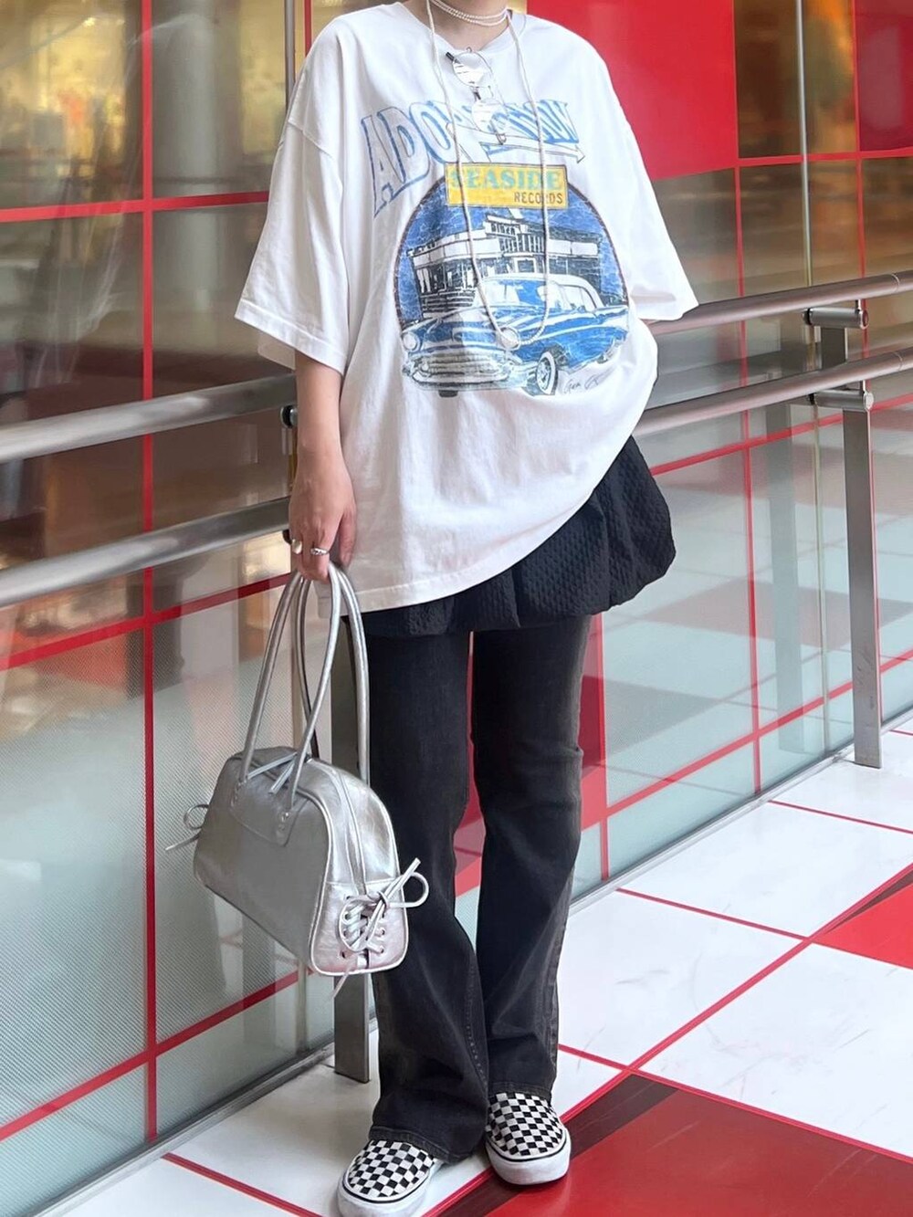 ブラック系のデニムパンツ、ホワイト系のTシャツ/カットソー、シルバー系のショルダーバッグを着用したレディースの夏コーディネートの2枚目の写真
