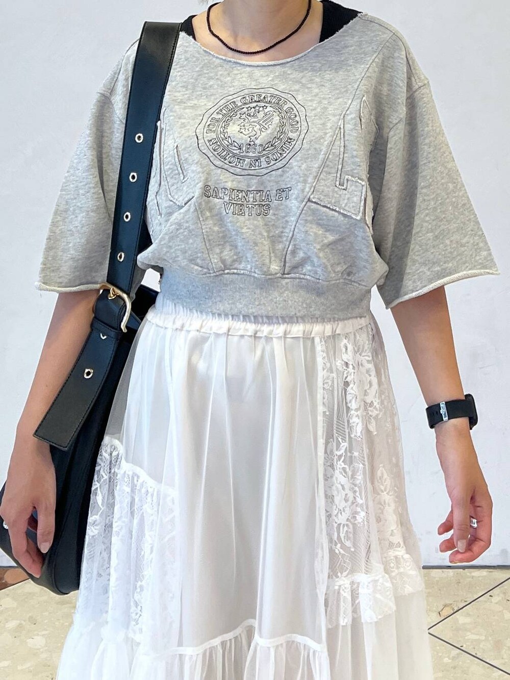 ブラック系のショルダーバッグ、ホワイト系のスカート、グレー系のTシャツ/カットソーを着用したレディースの夏コーディネートの2枚目の写真