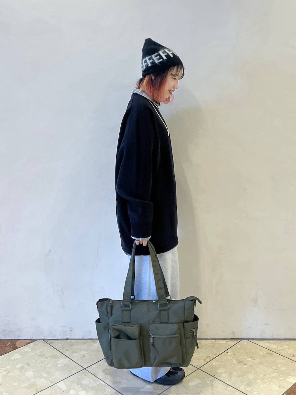 ブラック系のニット/セーター、グリーン系のボストンバッグ、グレー系のスウェットパンツを着用したレディースの秋コーディネートの2枚目の写真