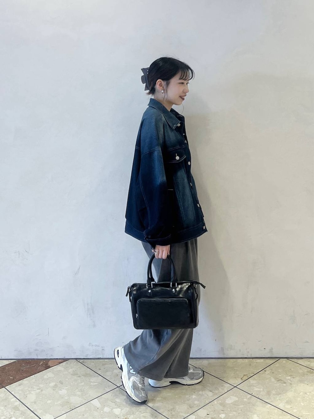 ブルー系のブルゾン、ブラック系のショルダーバッグ、グレー系のスウェットパンツを着用したレディースの春コーディネートの2枚目の写真