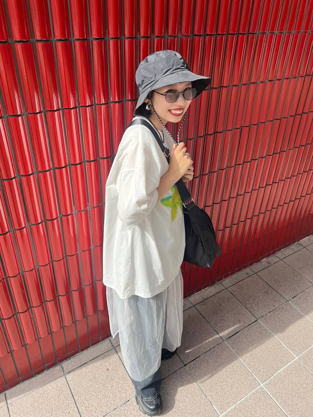 ブラック系のスニーカー、ブラック系のショルダーバッグ、ブルー系のデニムパンツを着用したレディースの夏コーディネートの4枚目の写真