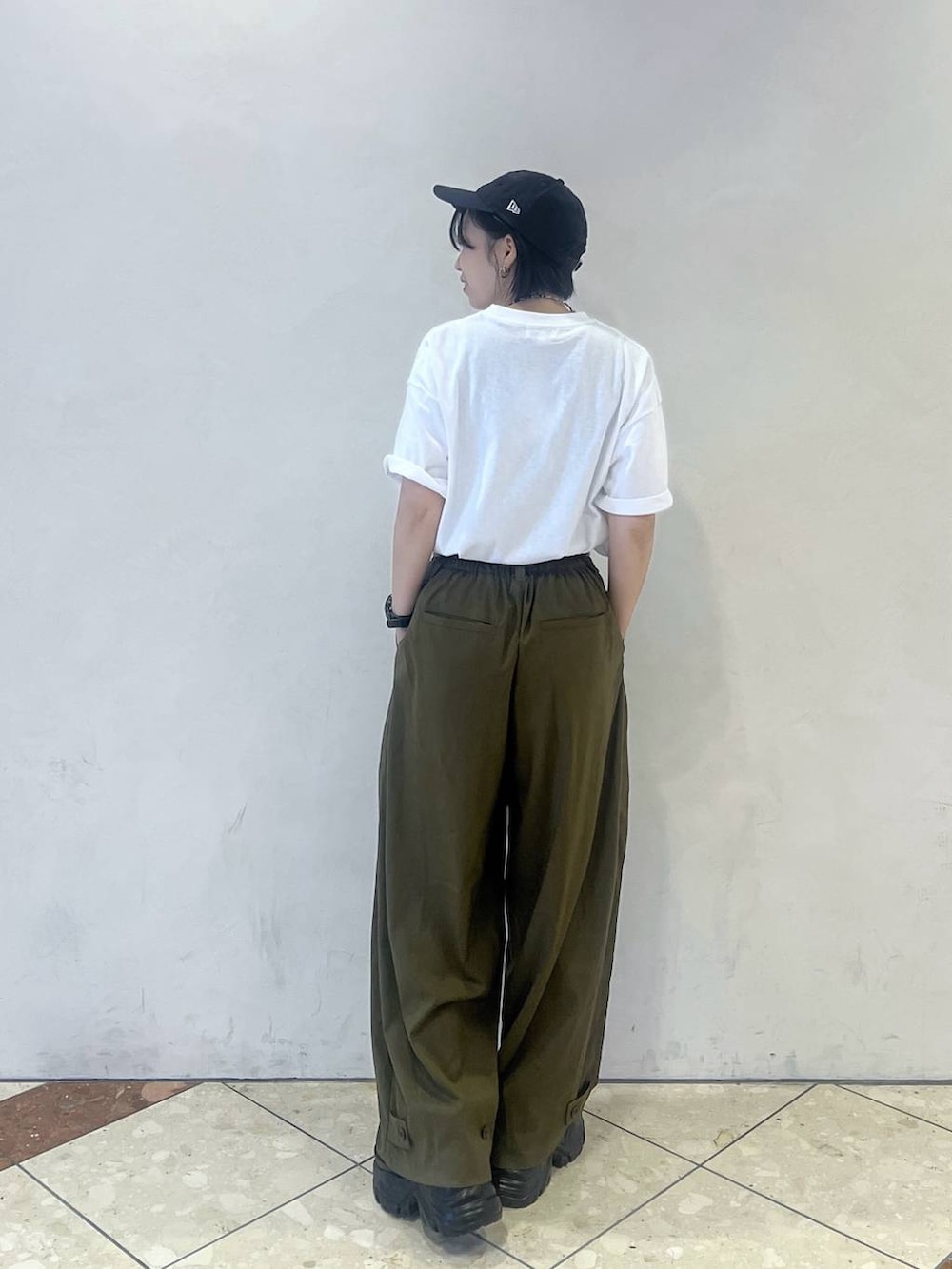 グリーン系のスラックス、ホワイト系のTシャツ/カットソー、ブラック系のスニーカーを着用したレディースの夏コーディネートの2枚目の写真