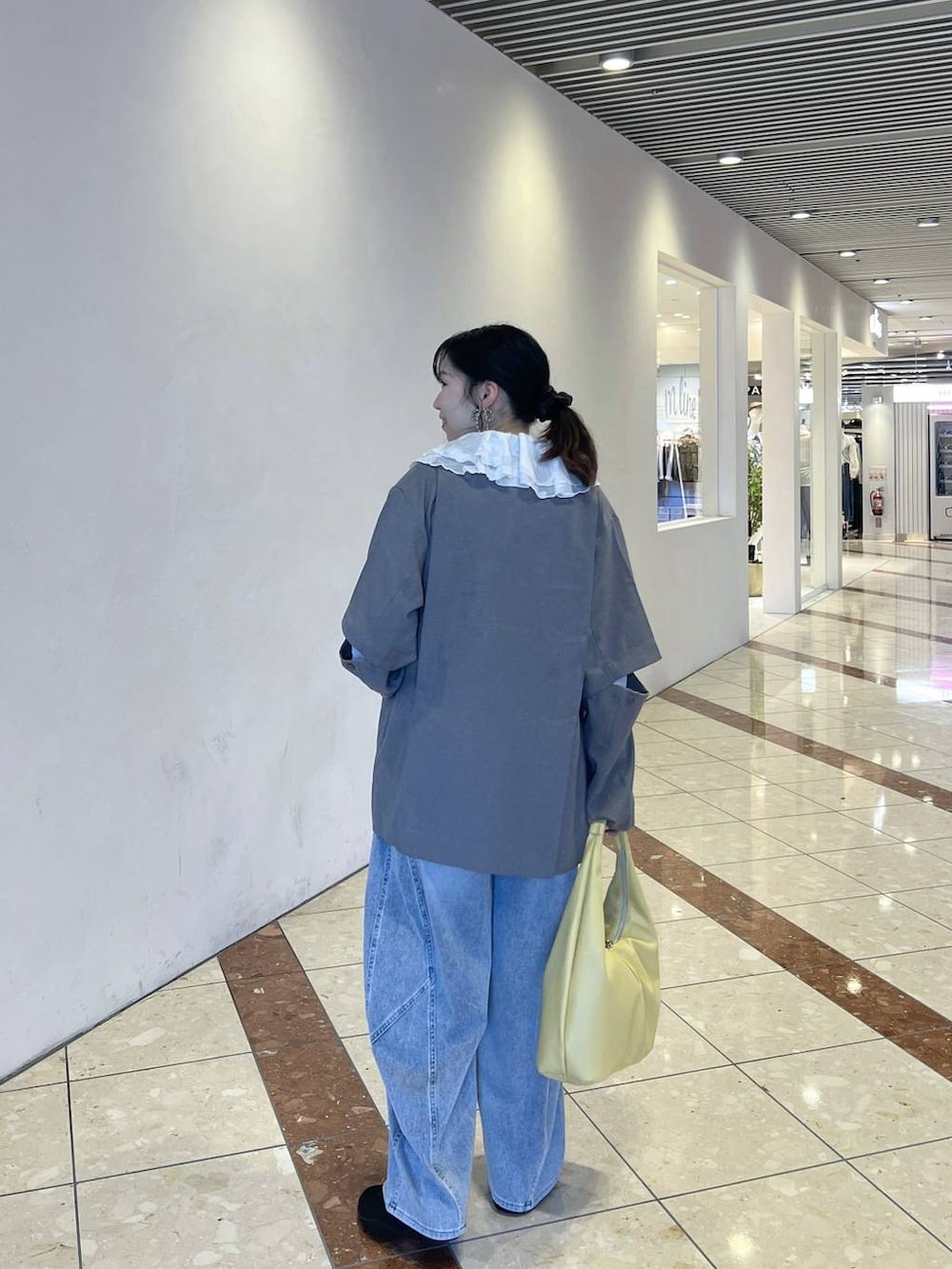 ブラック系のスニーカー、イエロー系のトートバッグ、グレー系のテーラードジャケットを着用したレディースの春コーディネートの4枚目の写真