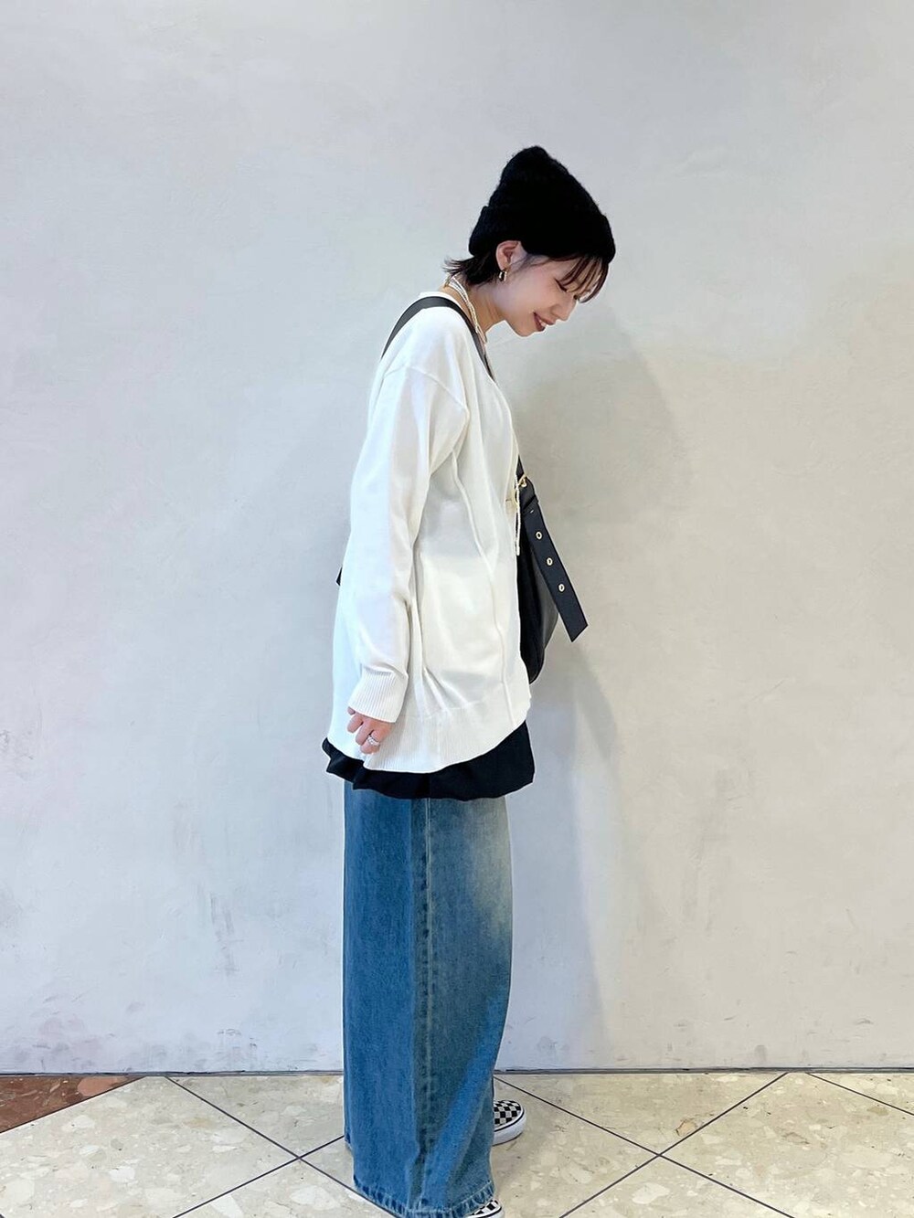 ブラック系のショルダーバッグ、ブルー系のデニムパンツ、ブラック系のスカートを着用したレディースの春コーディネートの2枚目の写真