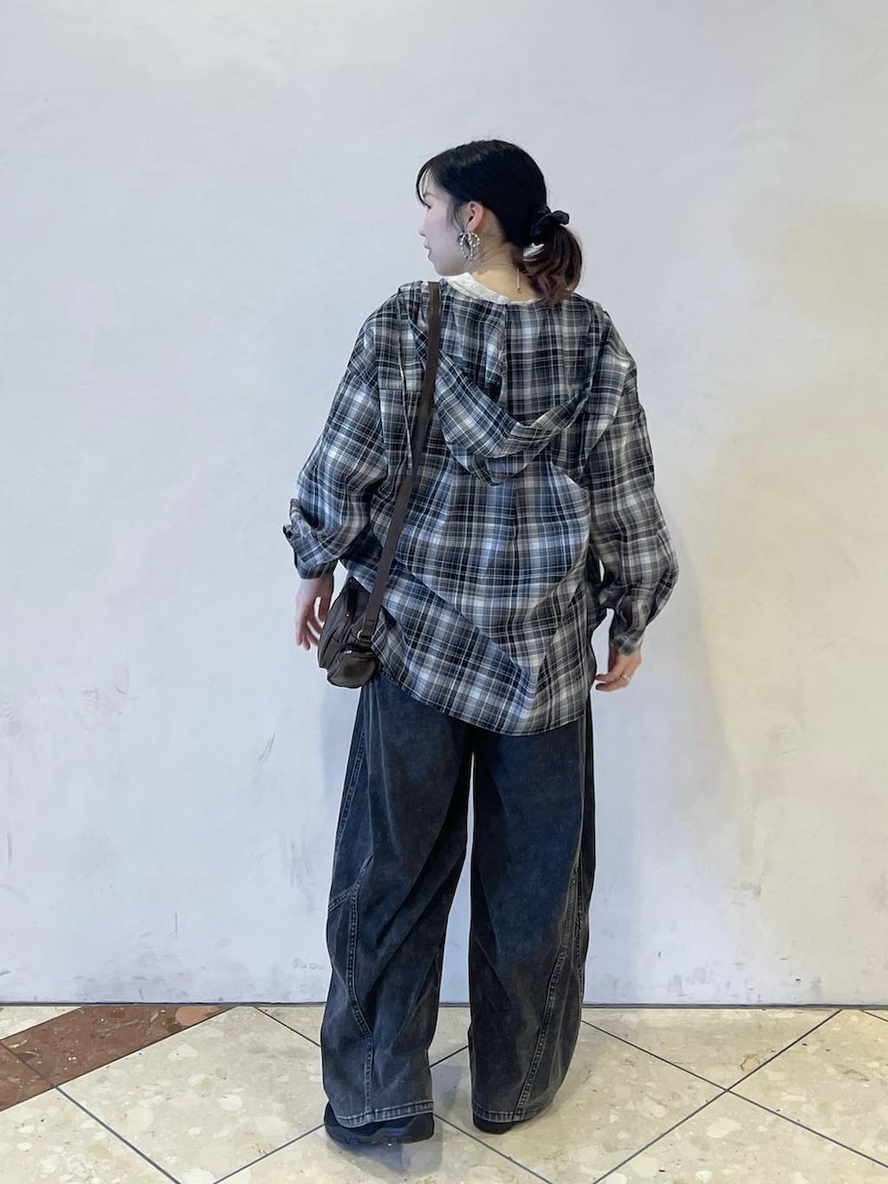 ブラック系のスニーカー、ブラック系のデニムパンツ、ブラウン系のショルダーバッグを着用したレディースの春コーディネートの3枚目の写真