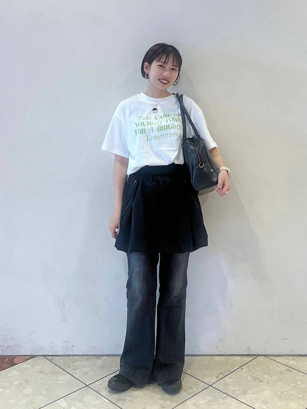 ブラック系のスカート、ブラック系のボストンバッグ、グレー系のデニムパンツを着用したレディースの春コーディネートの2枚目の写真