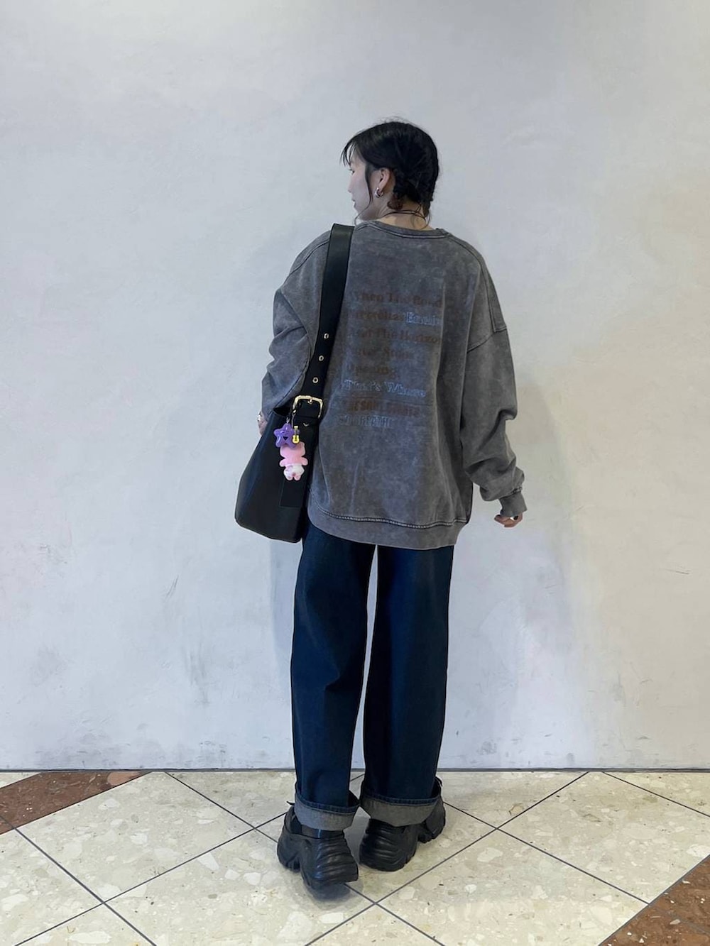 ブラック系のブーツ、ブラック系のショルダーバッグ、ブルー系のスラックスを着用したレディースの冬コーディネートの3枚目の写真