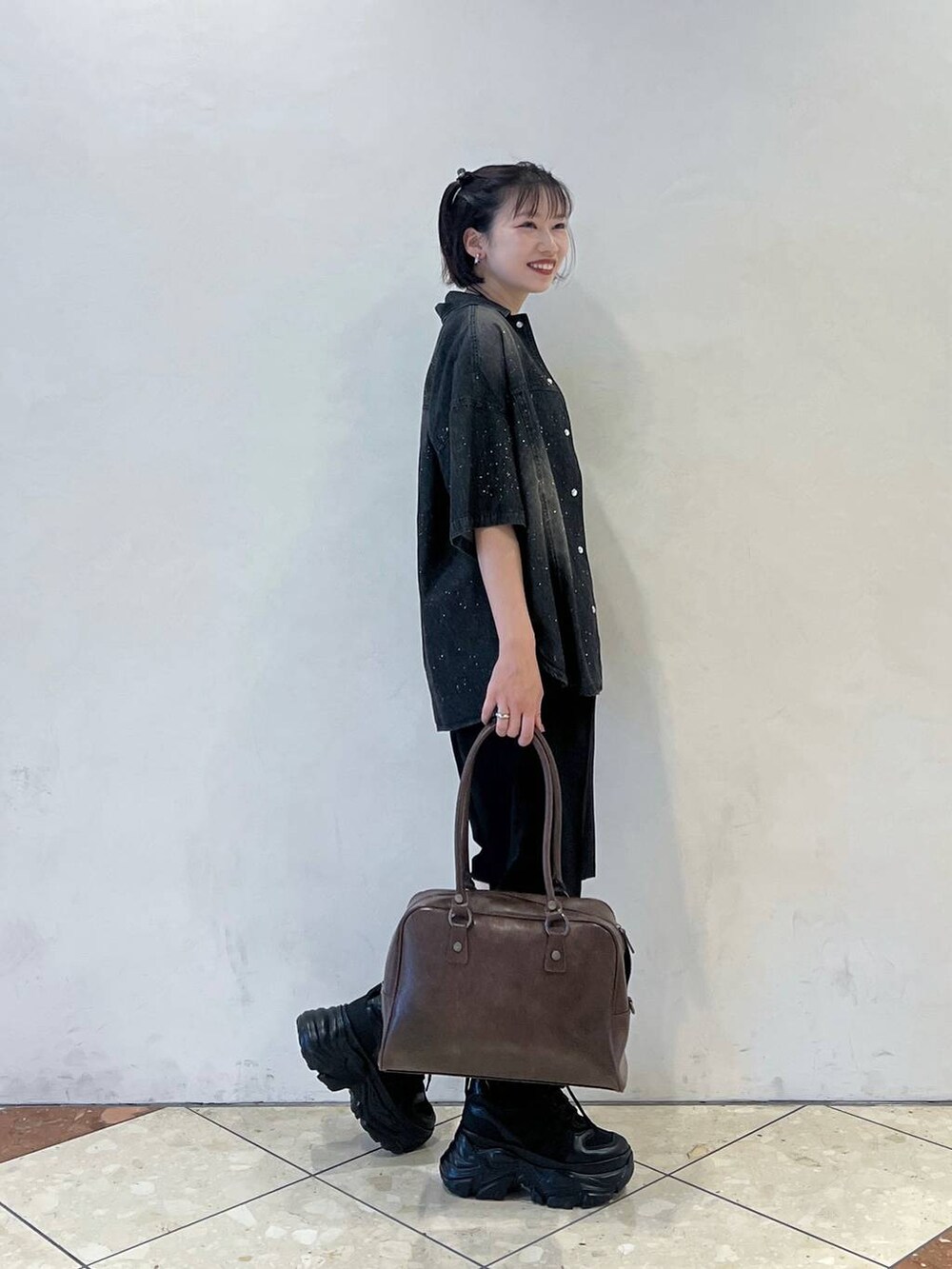 ブラック系のスニーカー、ブラウン系のボストンバッグ、ブラック系のタンクトップを着用したレディースの夏コーディネートの2枚目の写真