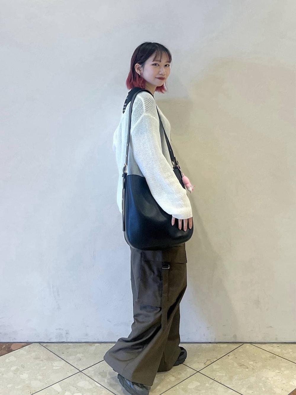 ブラック系のショルダーバッグ、ホワイト系のニット/セーター、ブラウン系のスラックスを着用したレディースの秋コーディネートの2枚目の写真