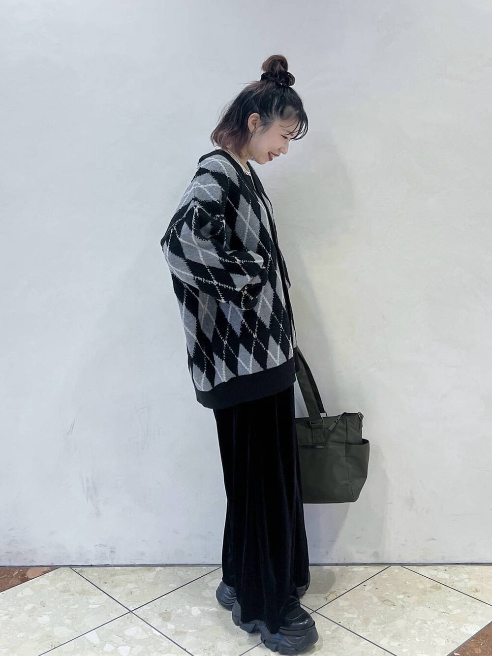 ブラック系のブーツ、グリーン系のボストンバッグ、ブラック系のその他パンツを着用したレディースの秋コーディネートの2枚目の写真