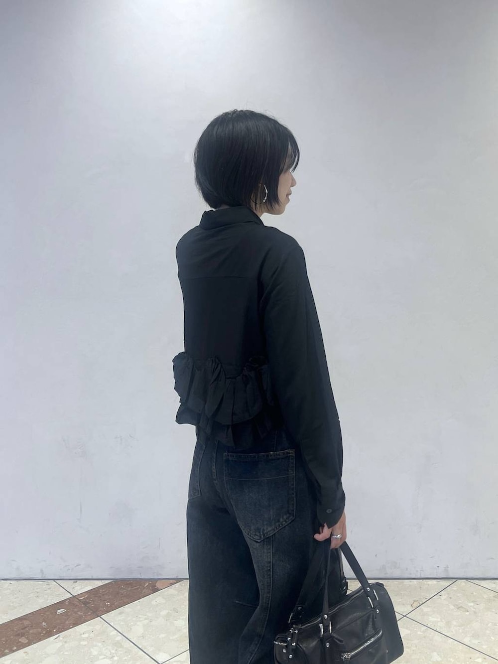 ブラック系のショルダーバッグ、ブルー系のデニムパンツ、ブラック系のスニーカーを着用したレディースの秋コーディネートの2枚目の写真