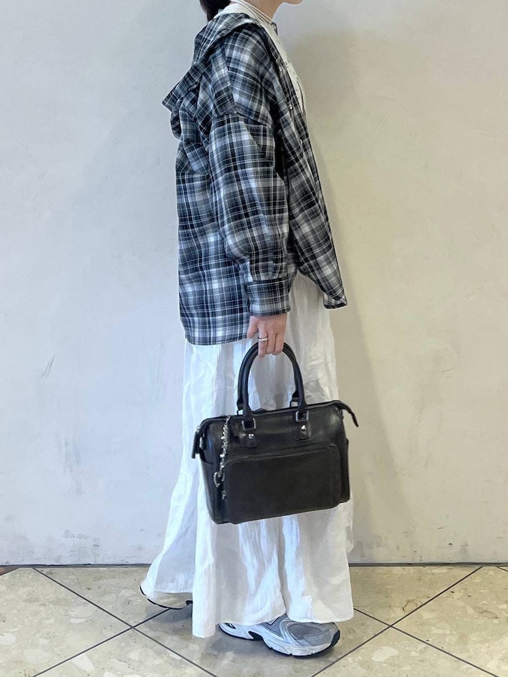 ブラック系のショルダーバッグ、ホワイト系のスカート、ベージュ系のTシャツ/カットソーを着用したレディースの春コーディネートの2枚目の写真