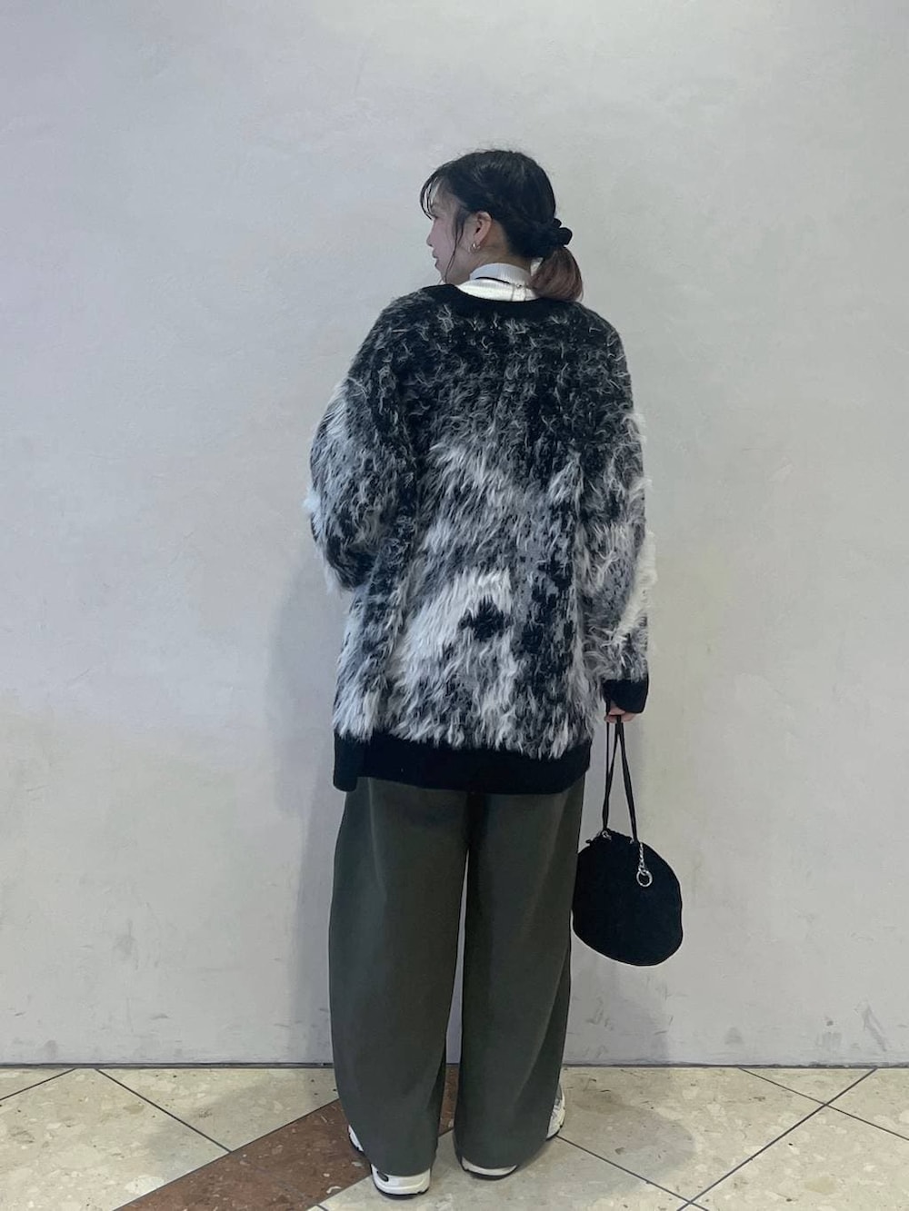 ブラック系のカーディガン/ボレロ、ブラック系のハンドバッグ、ホワイト系のニット/セーターを着用したレディースの冬コーディネートの3枚目の写真