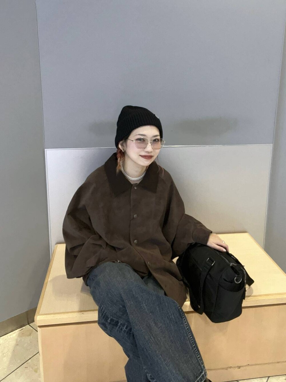 ブラック系のボストンバッグ、ブラウン系のブルゾン、ブルー系のデニムパンツを着用したレディースの秋コーディネートの2枚目の写真