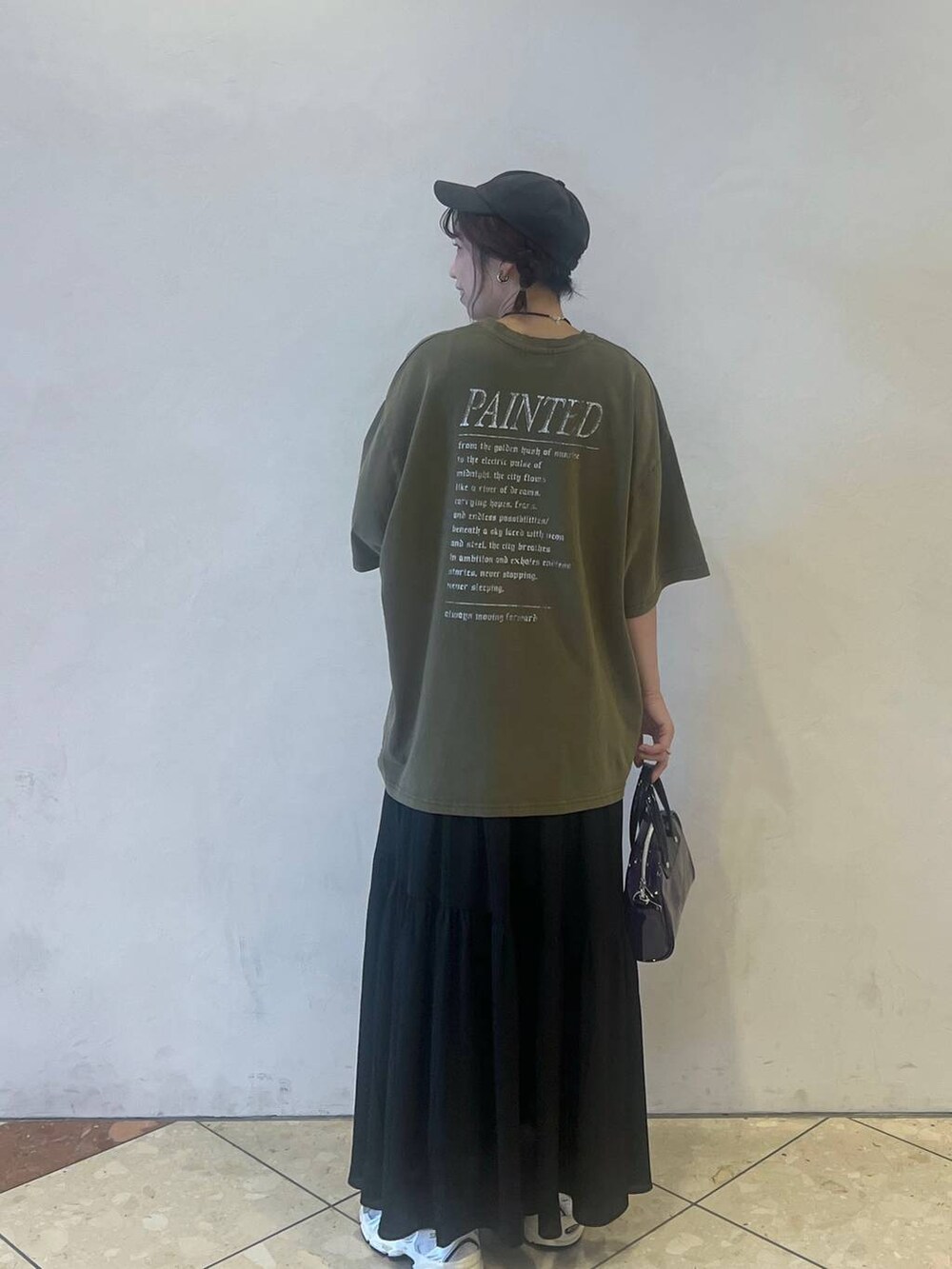 グリーン系のTシャツ/カットソー、ブラック系のスカートを着用したレディースの夏コーディネートの2枚目の写真