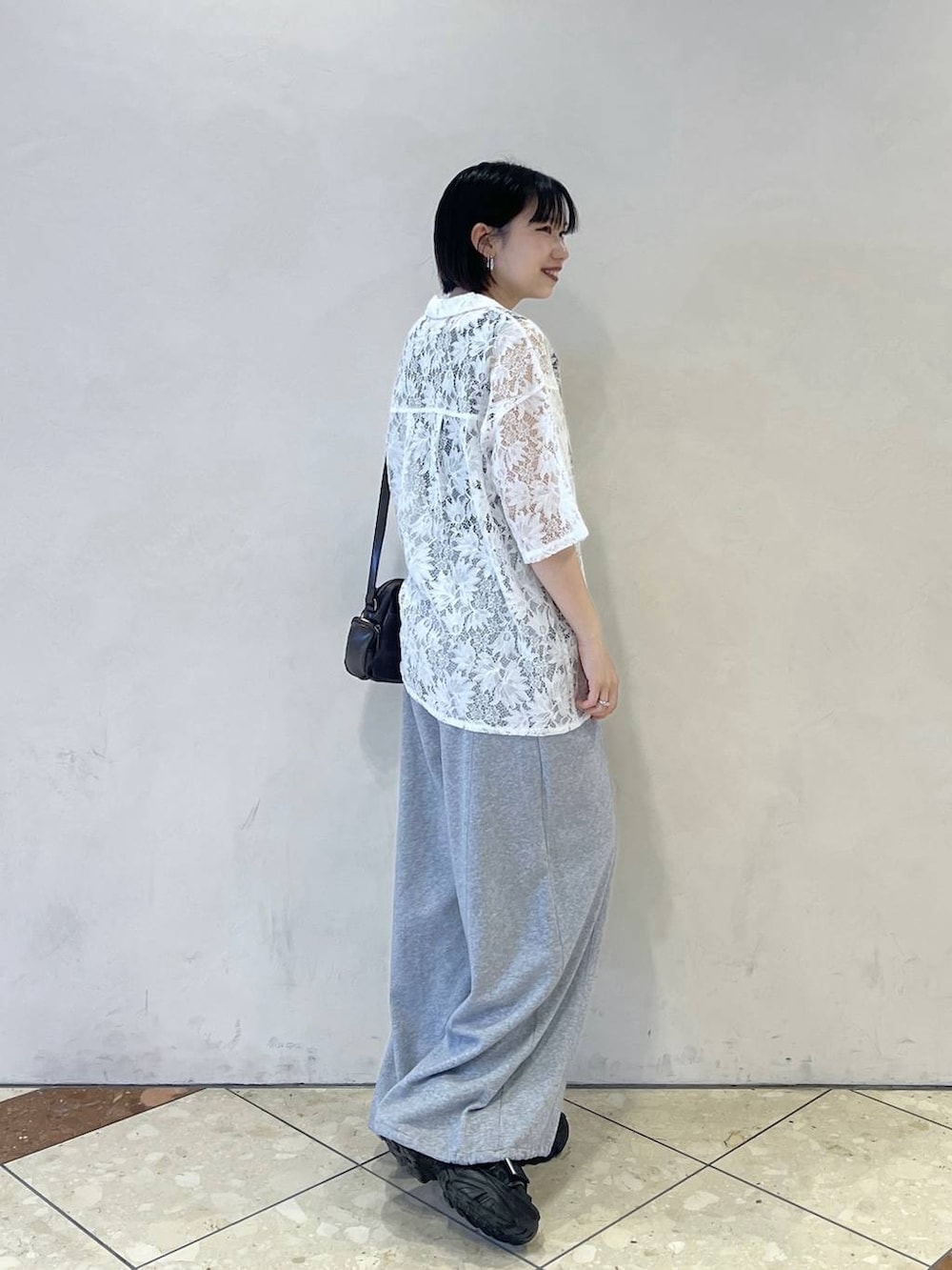 グレー系のスウェットパンツ、ブラウン系のショルダーバッグ、ブラック系のサンダルを着用したレディースの春コーディネートの2枚目の写真