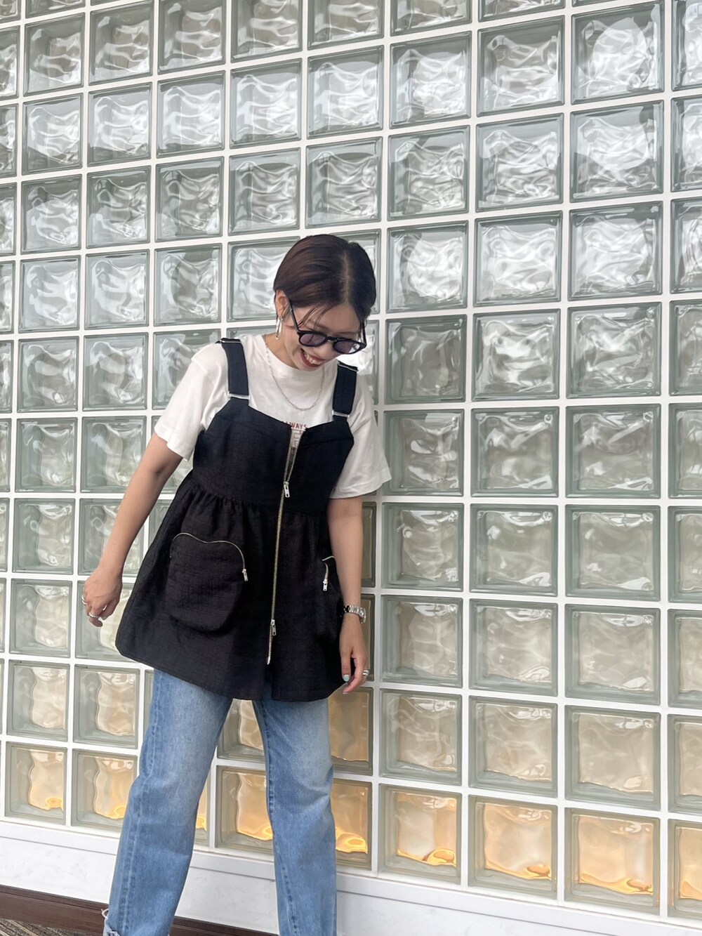 ブルー系のデニムパンツ、ブラック系のベスト、ホワイト系のTシャツ/カットソーを着用したレディースの夏コーディネートの3枚目の写真