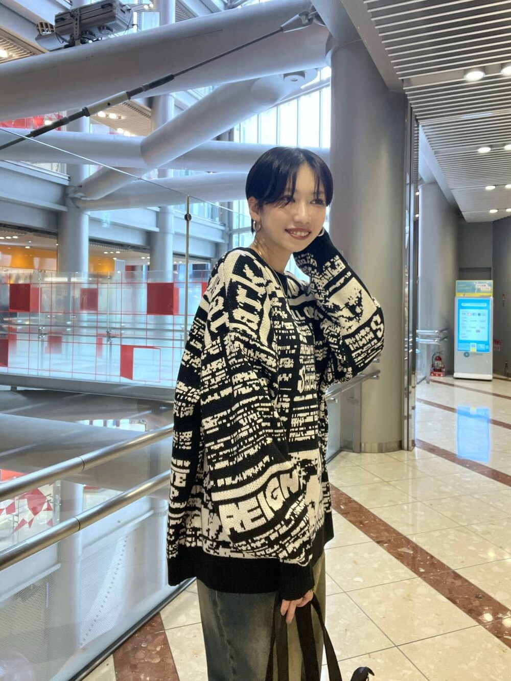 ブラック系のスニーカー、ブルー系のデニムパンツ、ブラック系のボストンバッグを着用したレディースの秋コーディネートの2枚目の写真