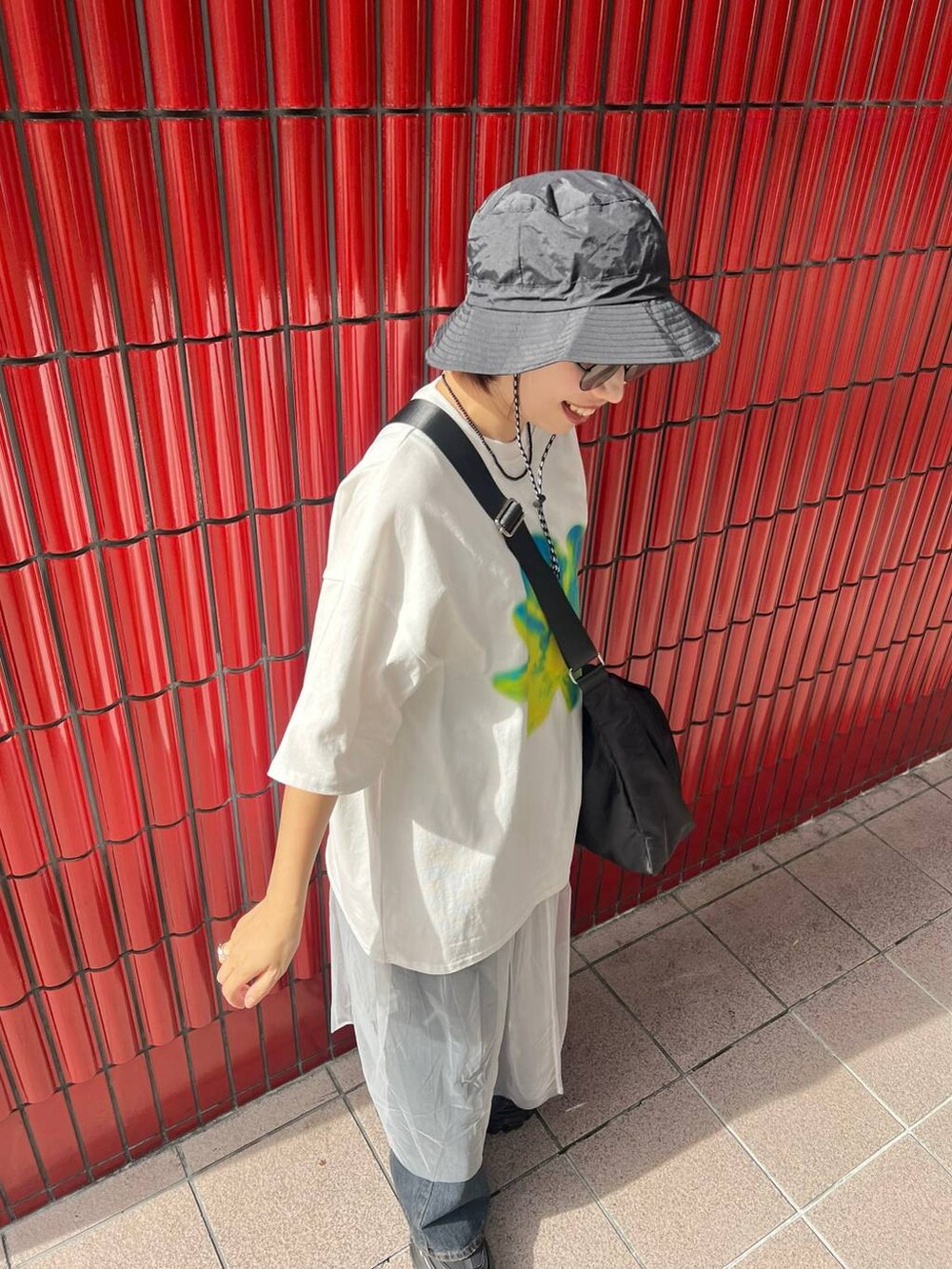 ブラック系のスニーカー、ブラック系のショルダーバッグ、ブルー系のデニムパンツを着用したレディースの夏コーディネートの3枚目の写真