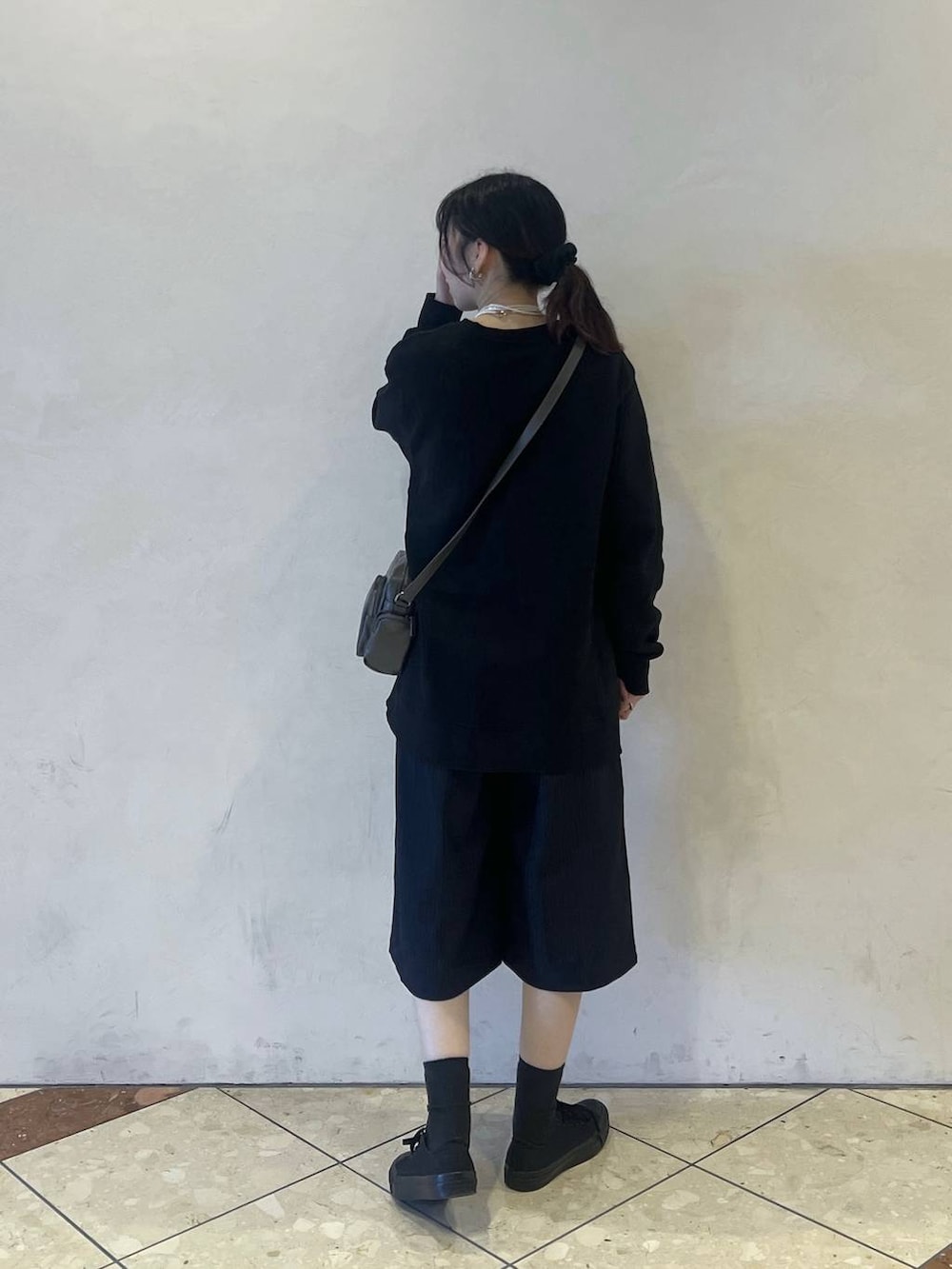 ブラック系のスウェット、グレー系のショルダーバッグ、ブルー系のスラックスを着用したレディースの春コーディネートの2枚目の写真