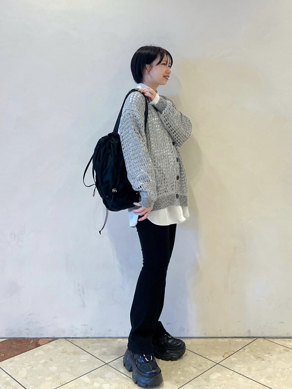 ブラック系のショルダーバッグ、グレー系のカーディガン/ボレロ、ブラック系のデニムパンツを着用したレディースの春コーディネートの2枚目の写真
